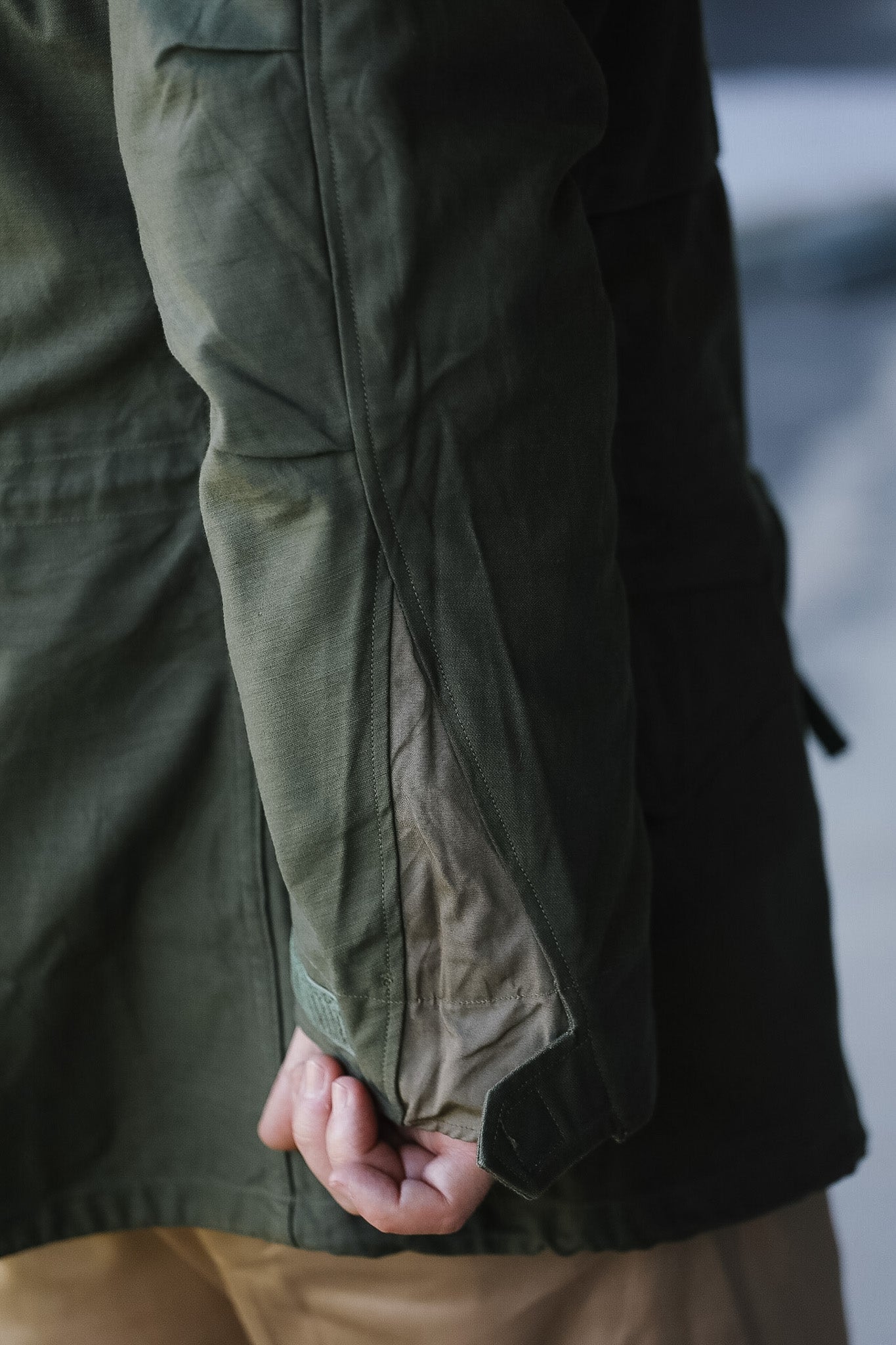 Close-up of a person wearing a green jacket with a blurred background
