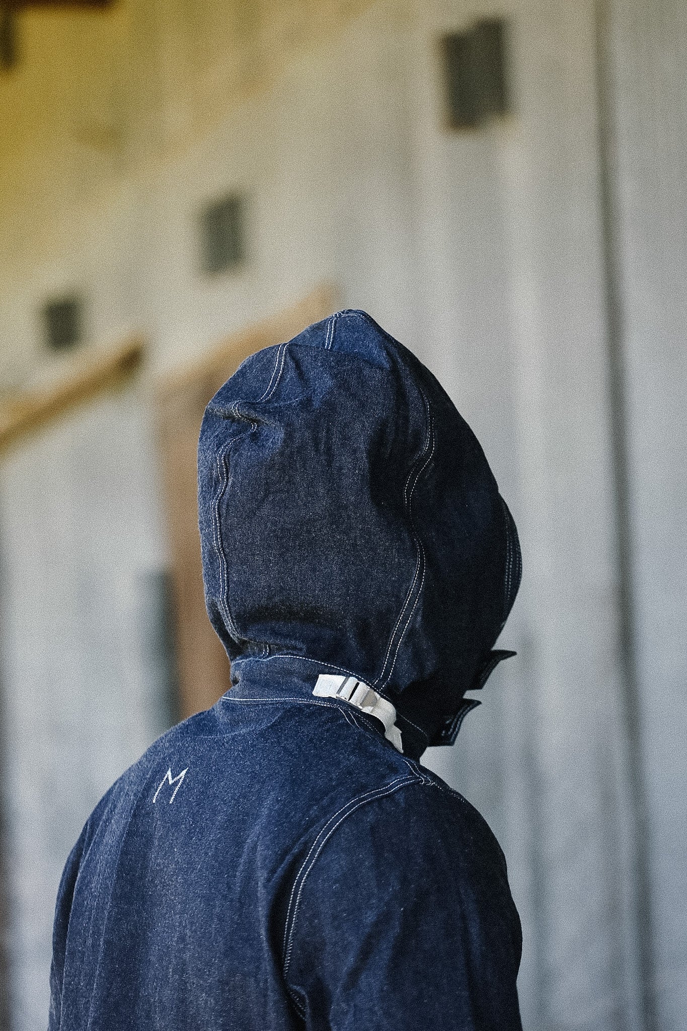Person wearing a blue denim hooded jacket in an indoor setting