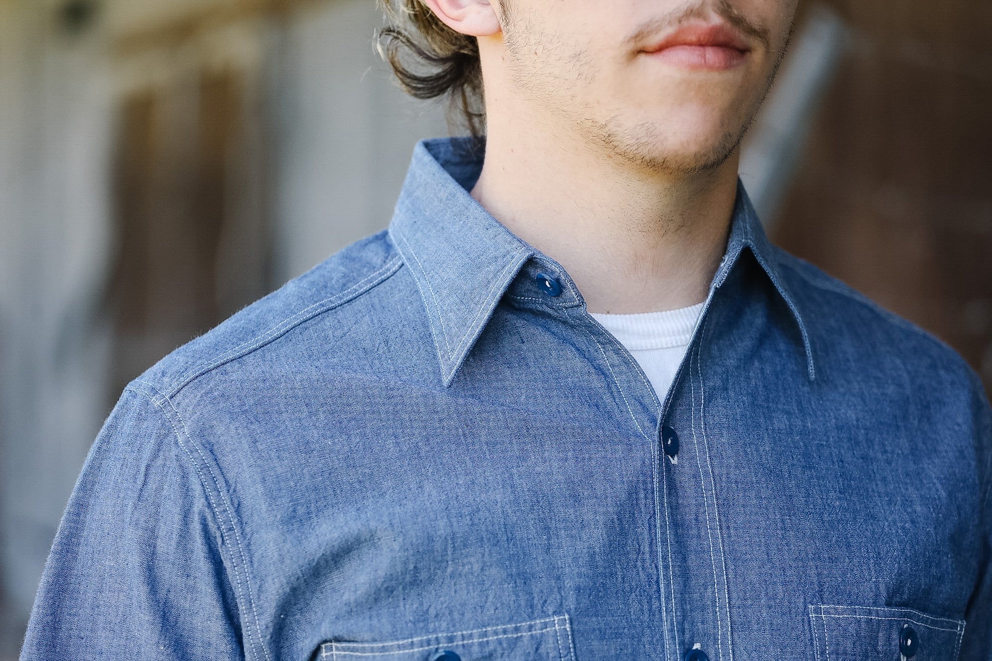 Man wearing a blue denim shirt with a blurred background