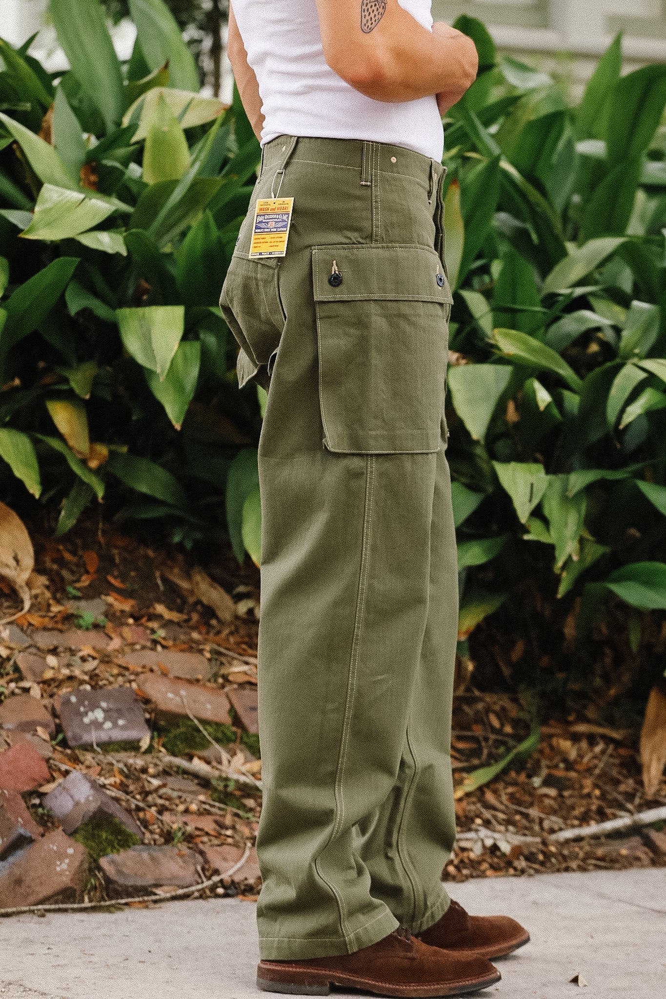 Person wearing green cargo pants with a visible brand label, standing outdoors.