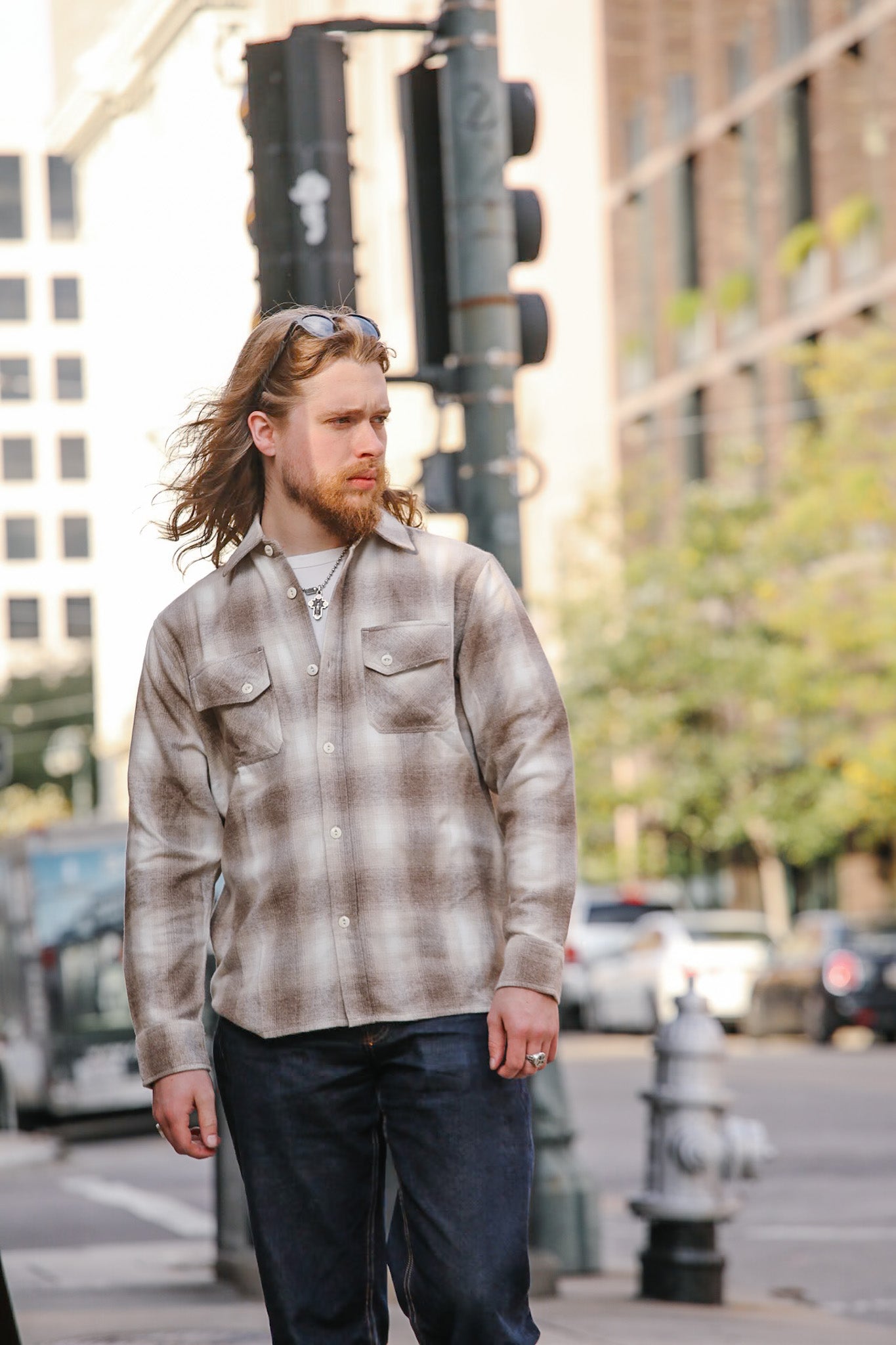 Man wearing a plaid shirt and sunglasses on a city street