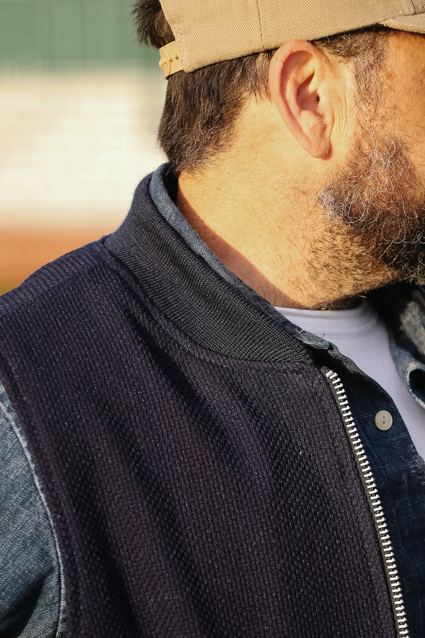 Man wearing a black vest over a white shirt with a blurred background