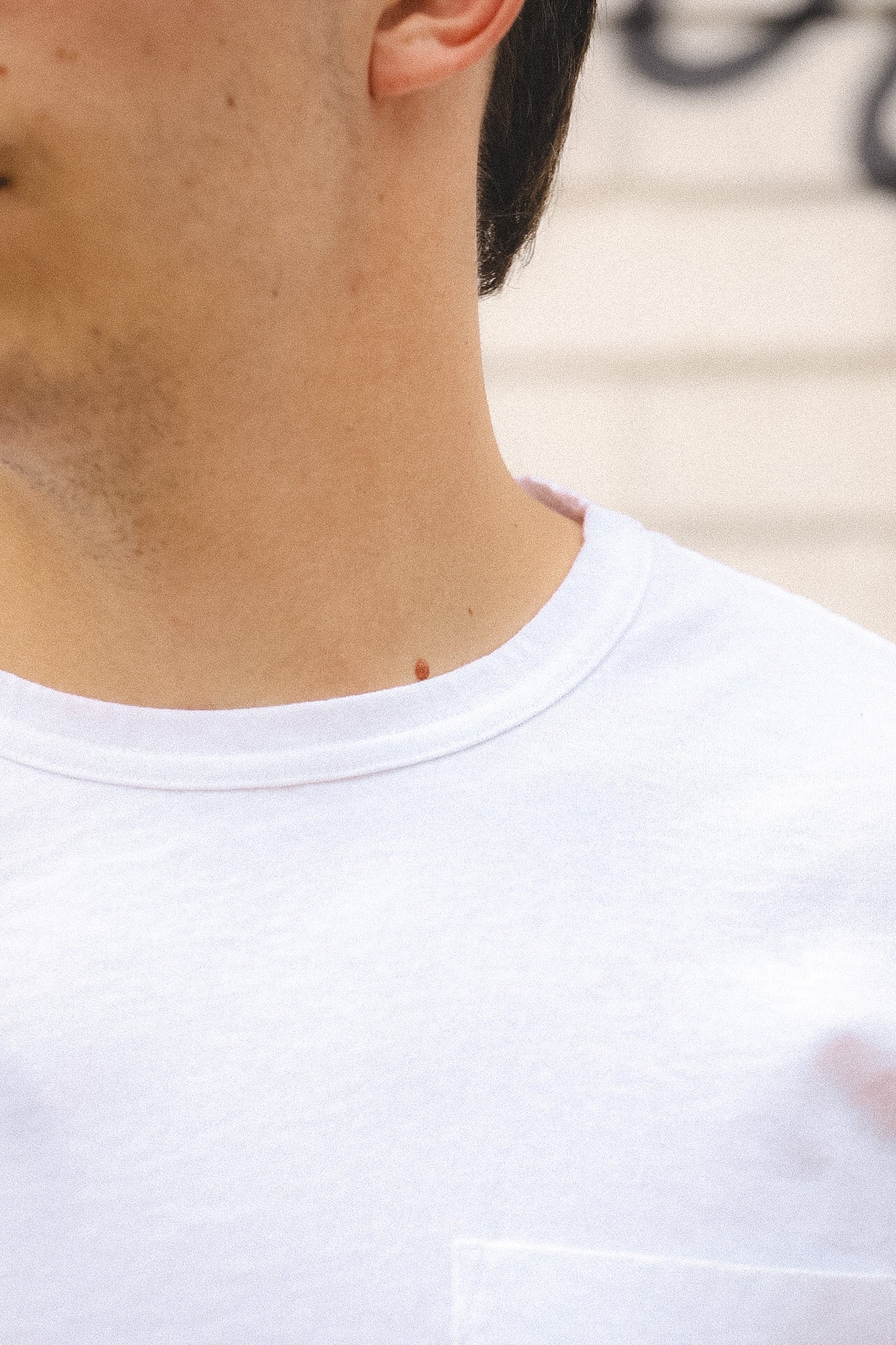 Close-up of a person wearing a white t-shirt with a blurred background