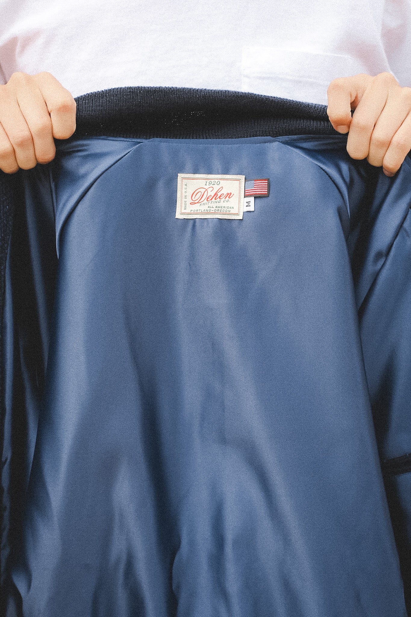Blue jacket with a brand label held open by hands