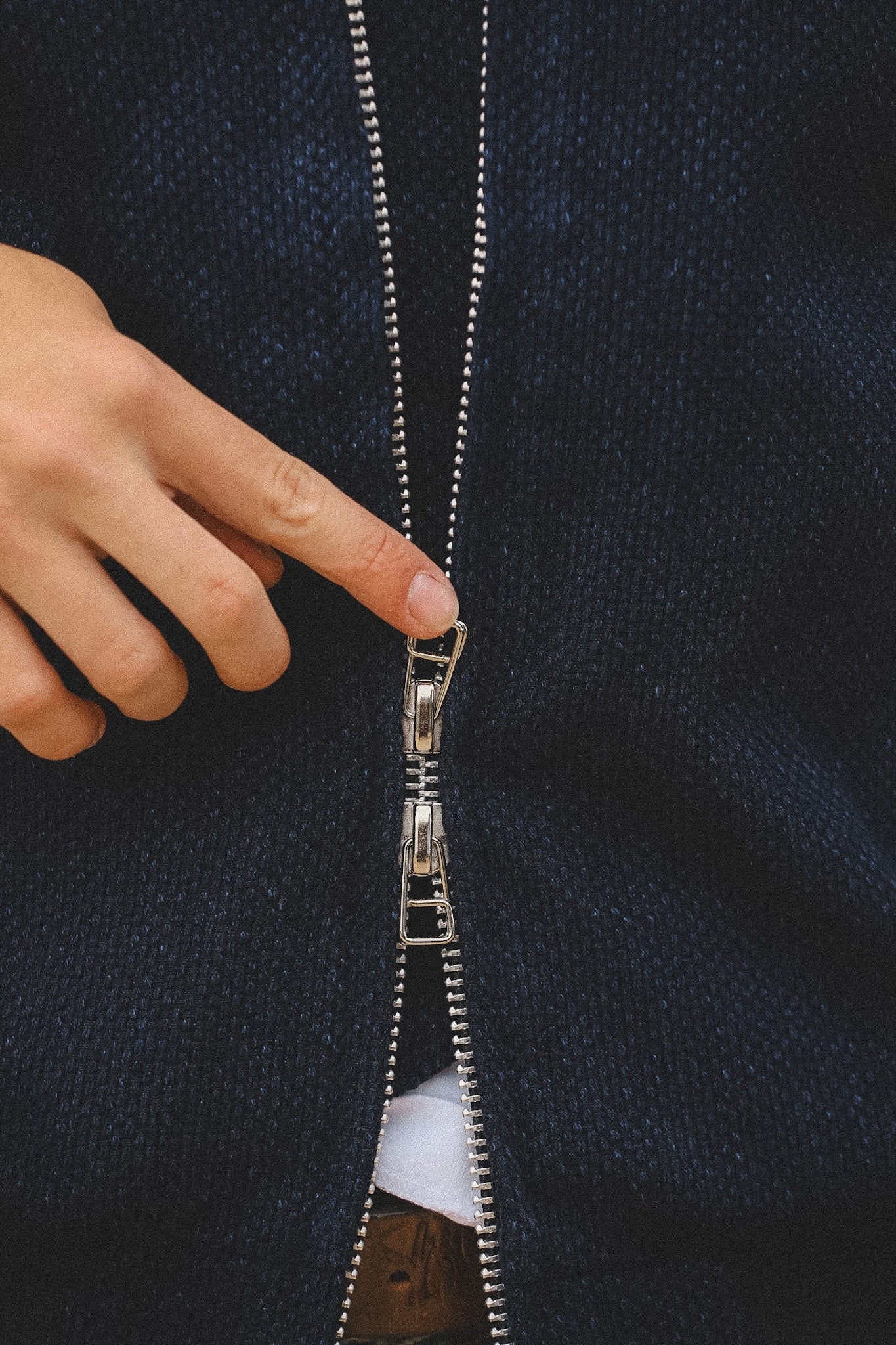 Hand zipping a dark blue jacket