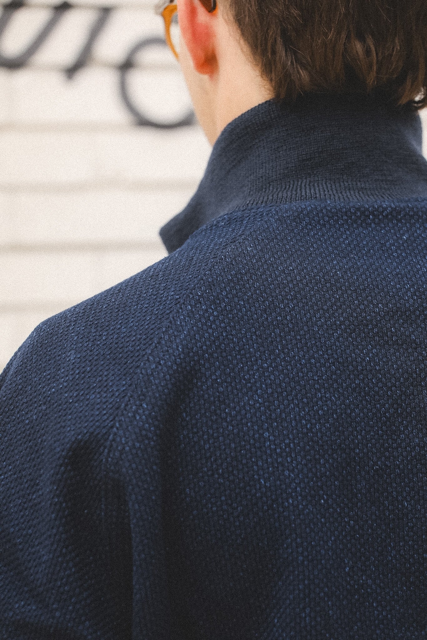 Person wearing a dark blue knitted sweater with a blurred background