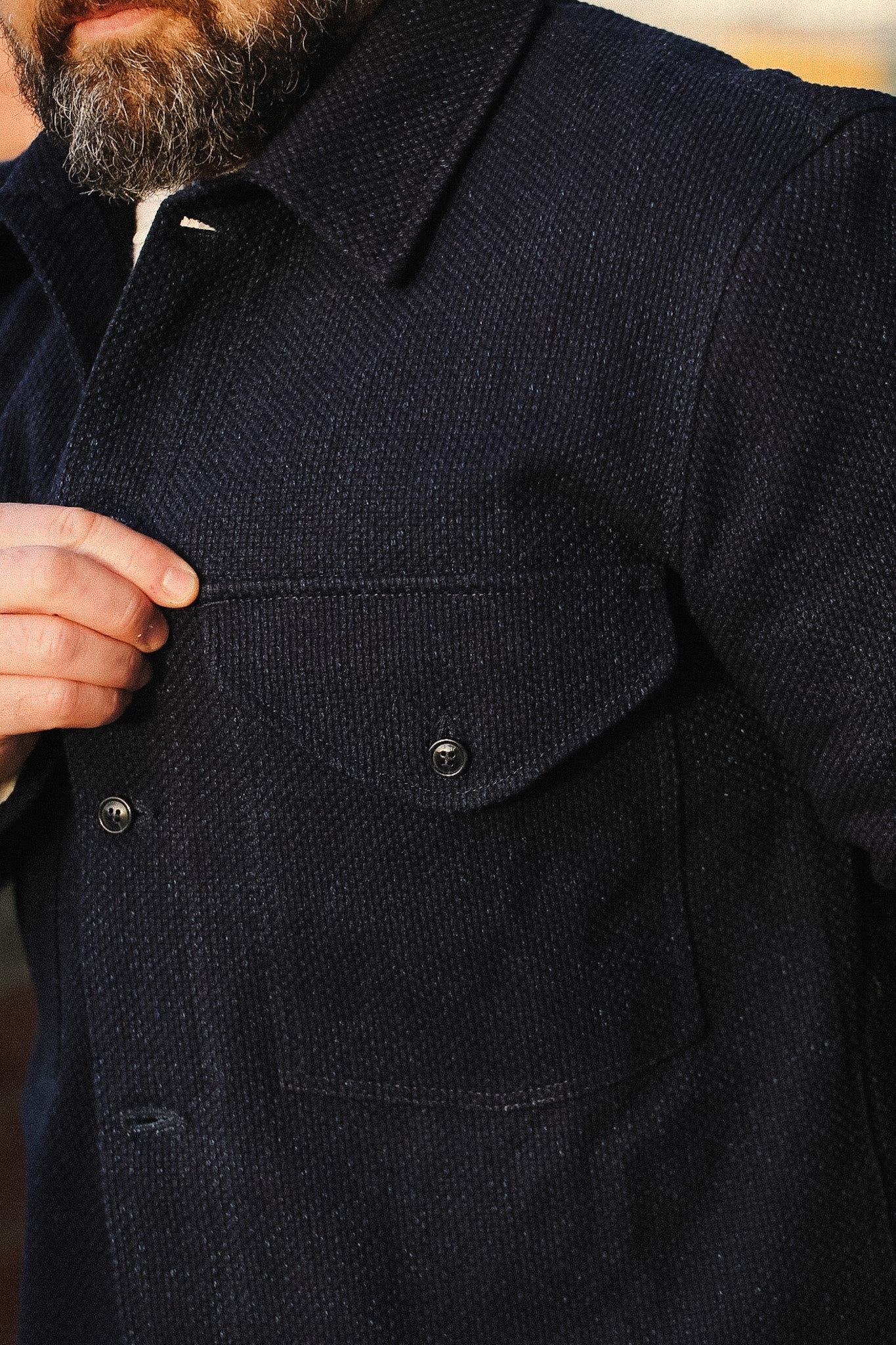 Close-up of a dark coat with a focus on the collar and buttons.