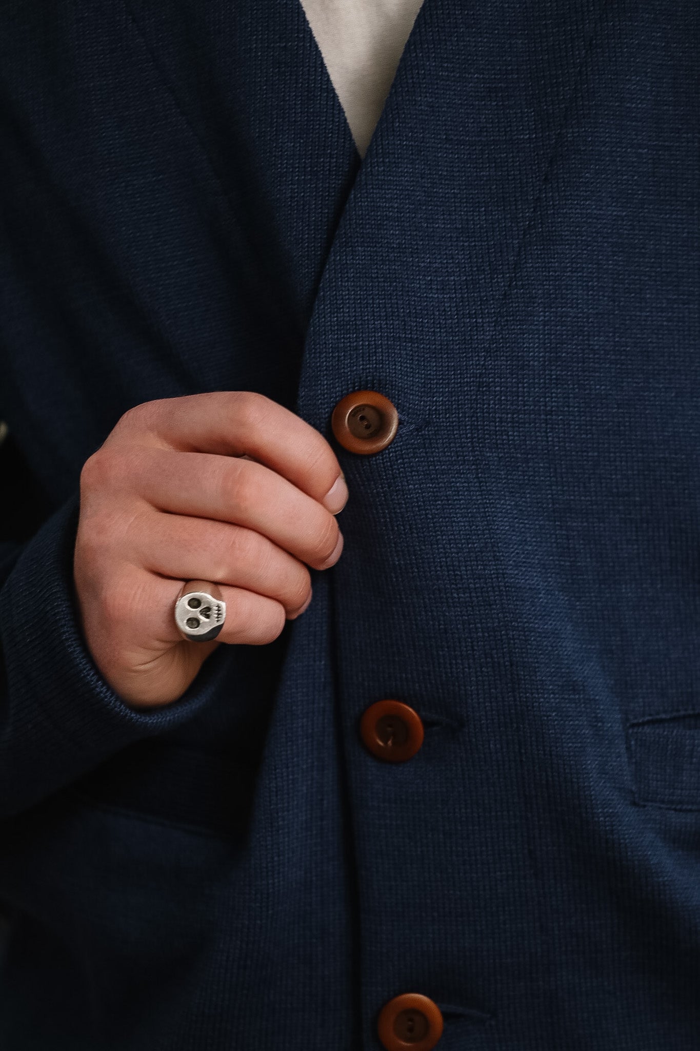 Close-up of a person wearing a navy blue suit with brown buttons, focusing on the jacket.
