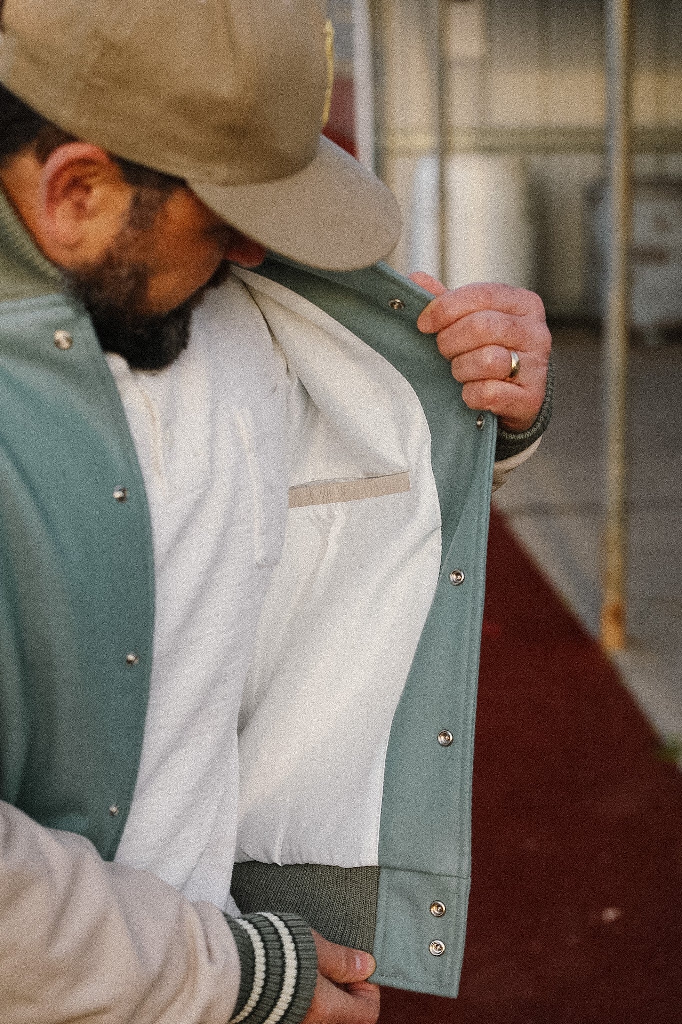 Person wearing a green jacket with a white shirt underneath, standing in an outdoor setting.
