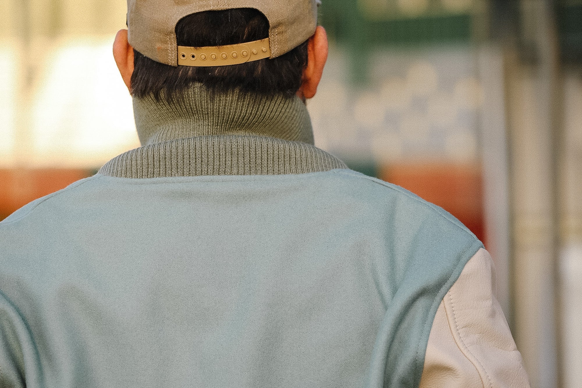 Person wearing a beige cap and light gray vest with a blurred background