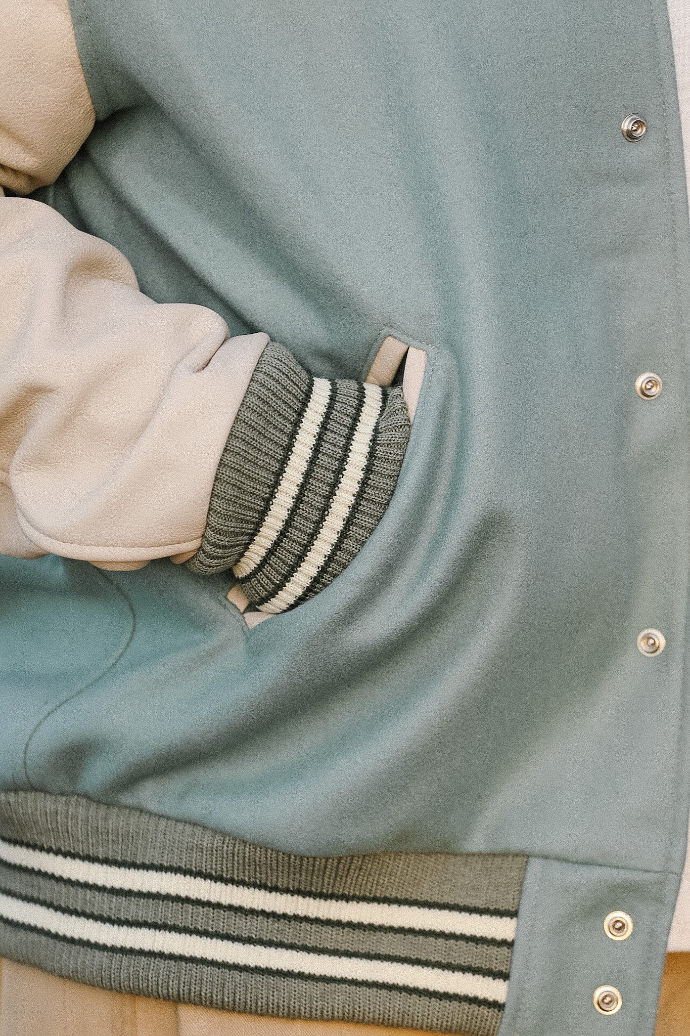 Close-up of a green varsity jacket with striped cuffs and collar.