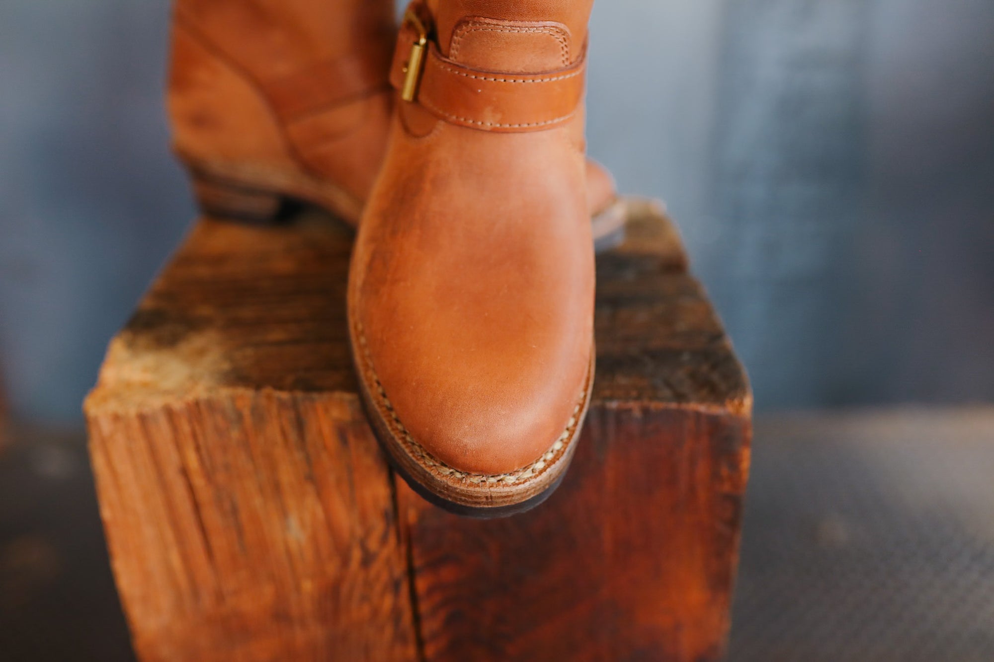 Brown leather boot on a wooden block with a blurred background