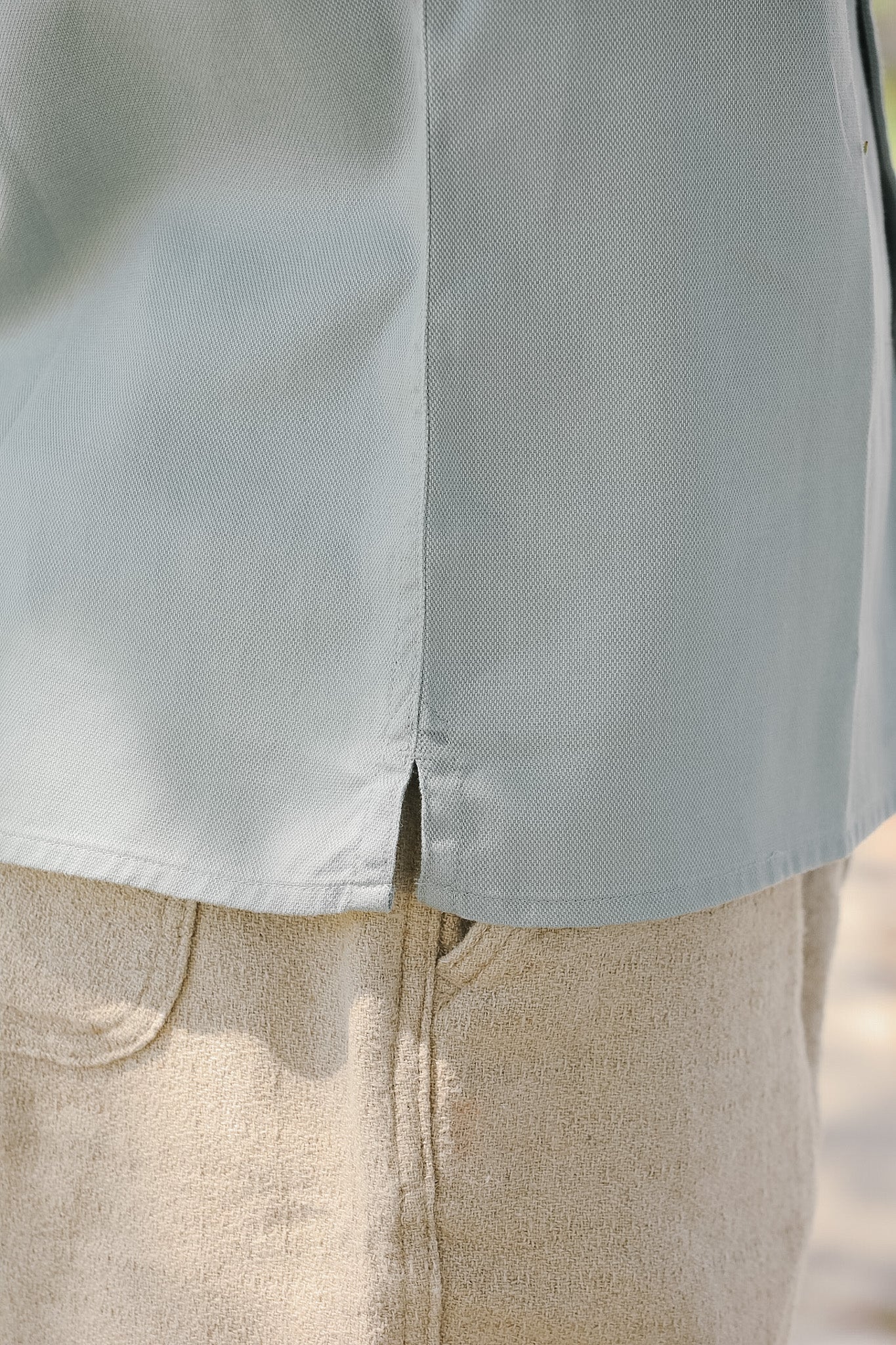 Close-up of a light blue shirt and beige pants with a blurred background