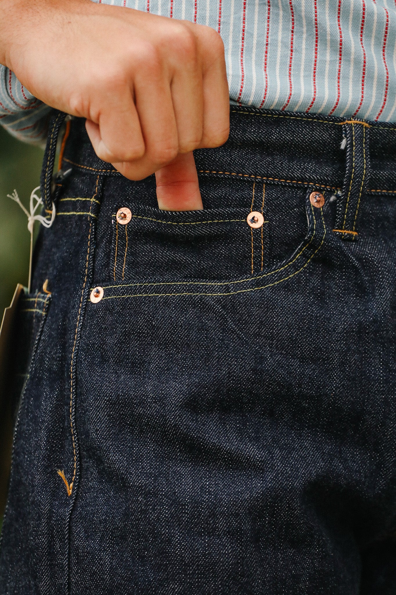 Close-up of a person wearing dark blue jeans with visible stitching and buttons.