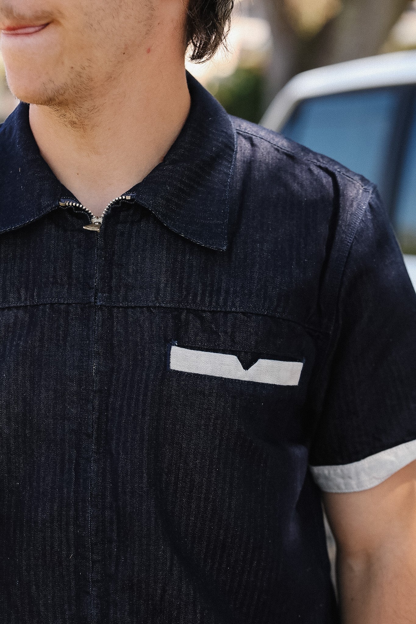 Person wearing a dark blue shirt with a white logo on the chest.