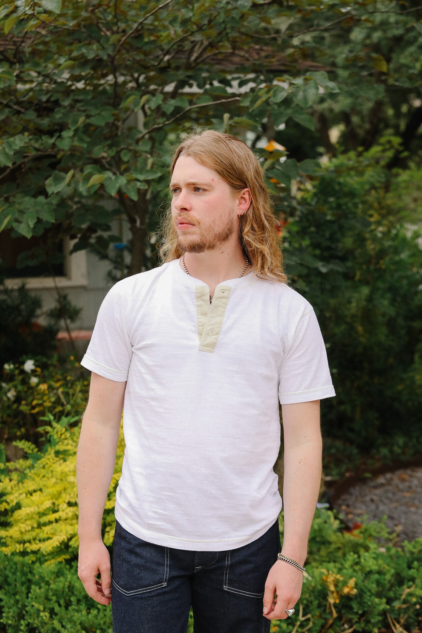 Man wearing a white t-shirt with a patterned collar in an outdoor setting