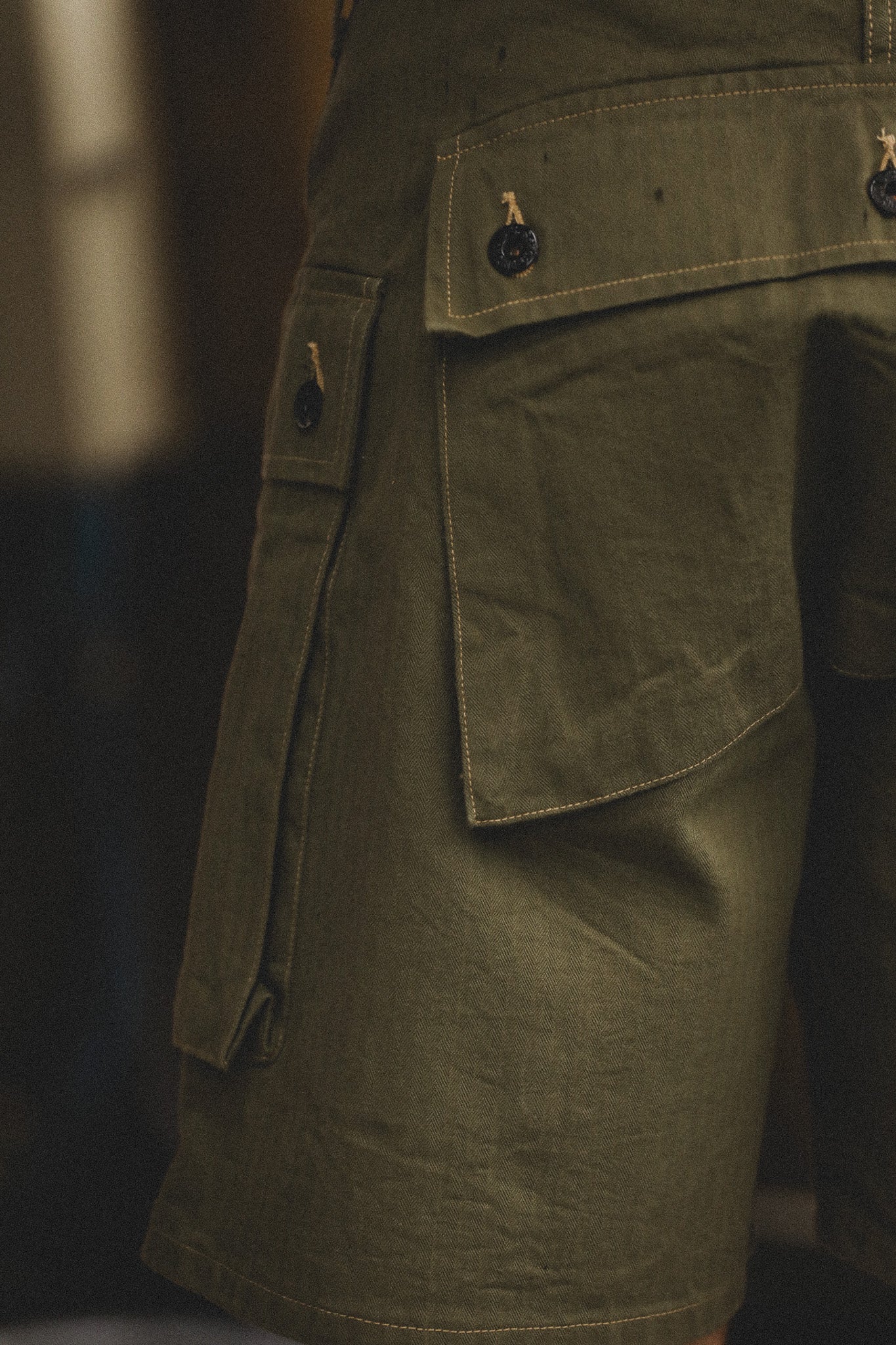 Close-up of a green military-style jacket with pockets on a dark background
