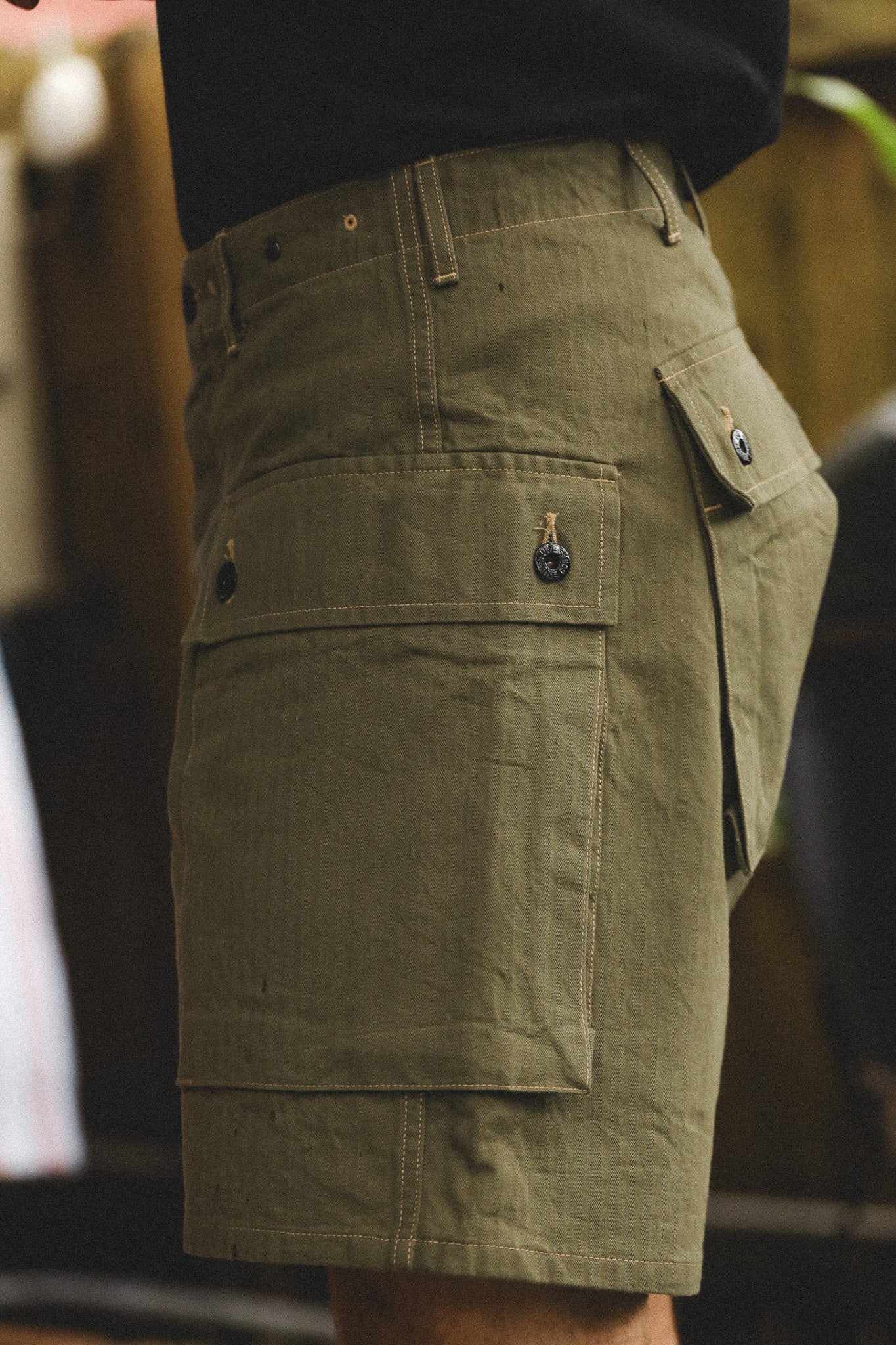 Green cargo shorts with multiple pockets on a blurred background