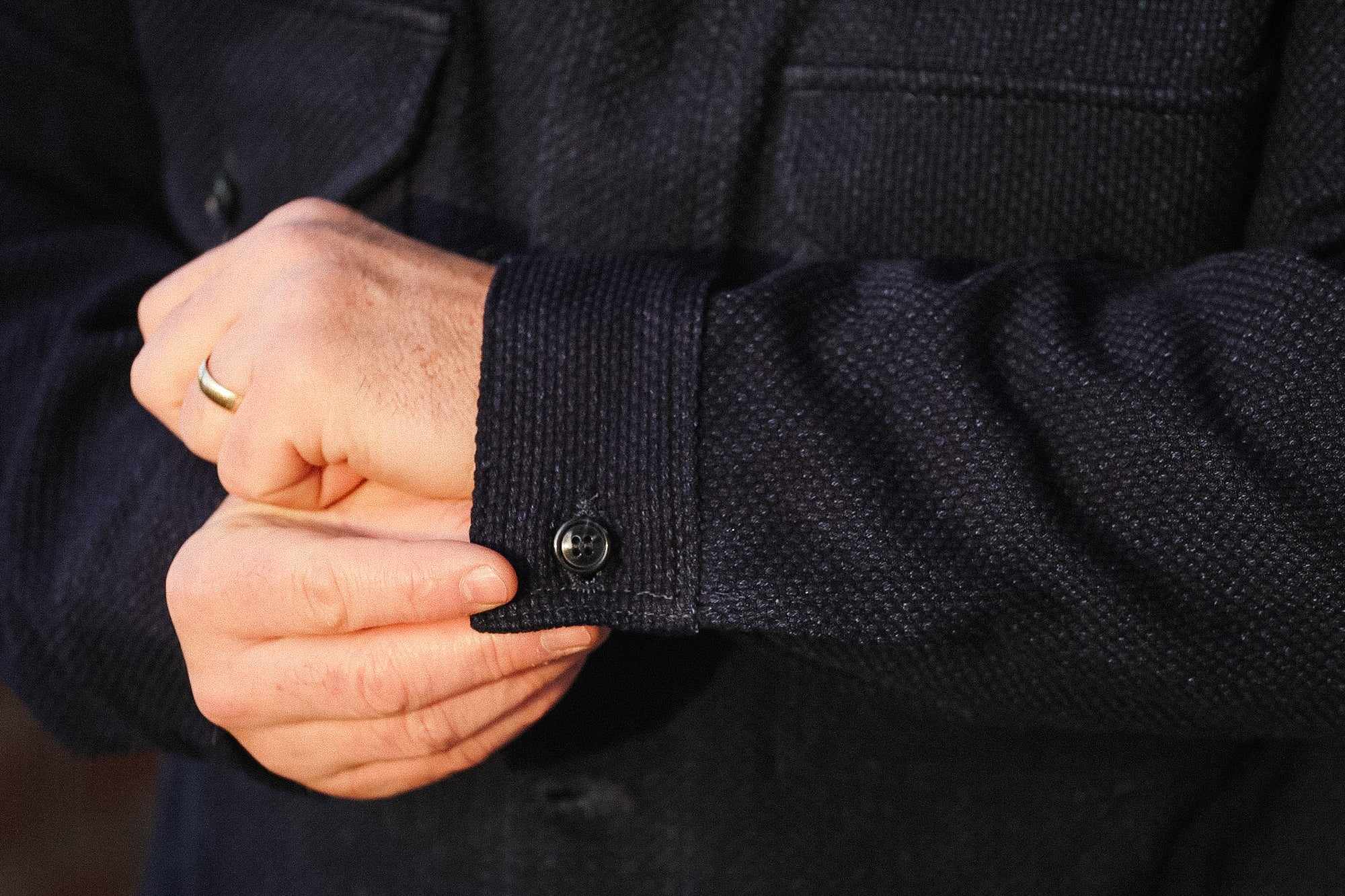 Close-up of a person wearing a dark coat with buttoned cuffs.
