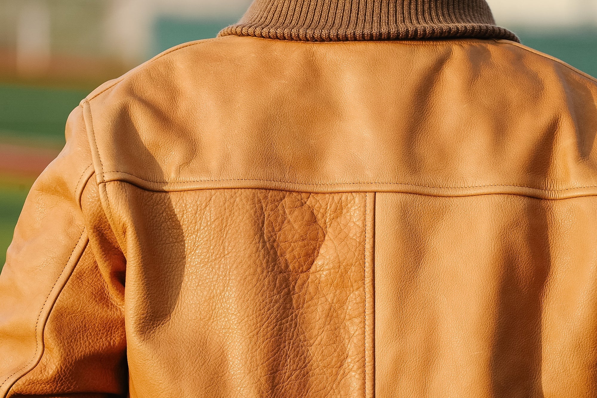 Brown leather jacket worn by a person with a blurred background