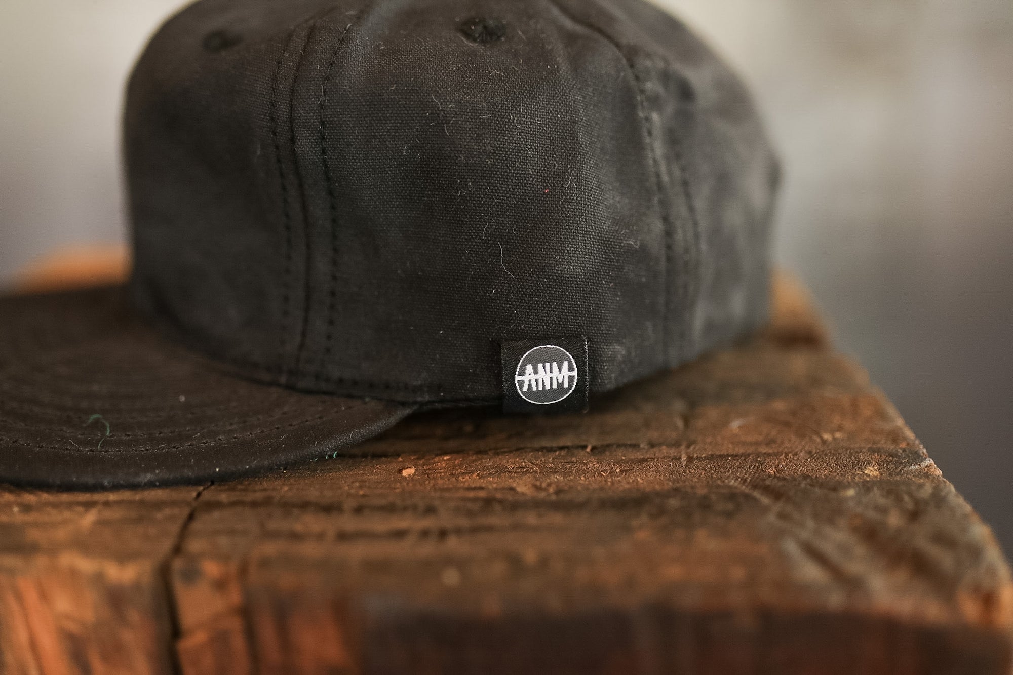 Black cap with a logo on a wooden surface