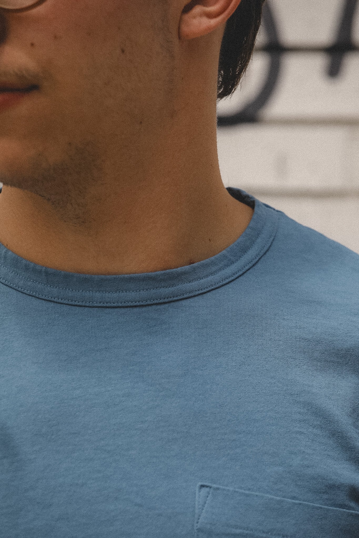 Close-up of a person wearing a blue t-shirt with a blurred background