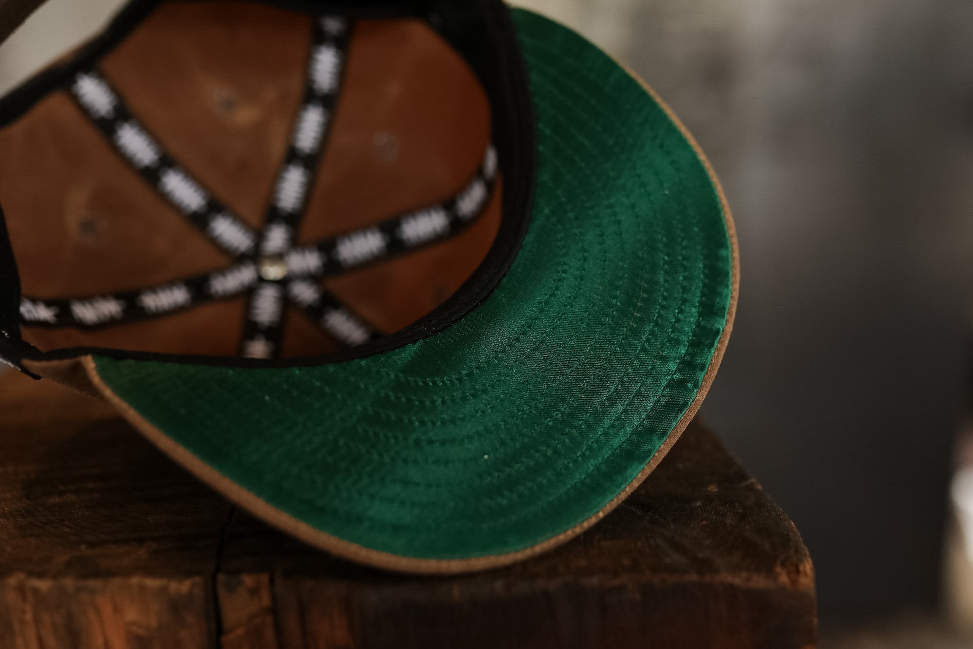 Two hats, one green and one brown with a decorative band, on a wooden surface.