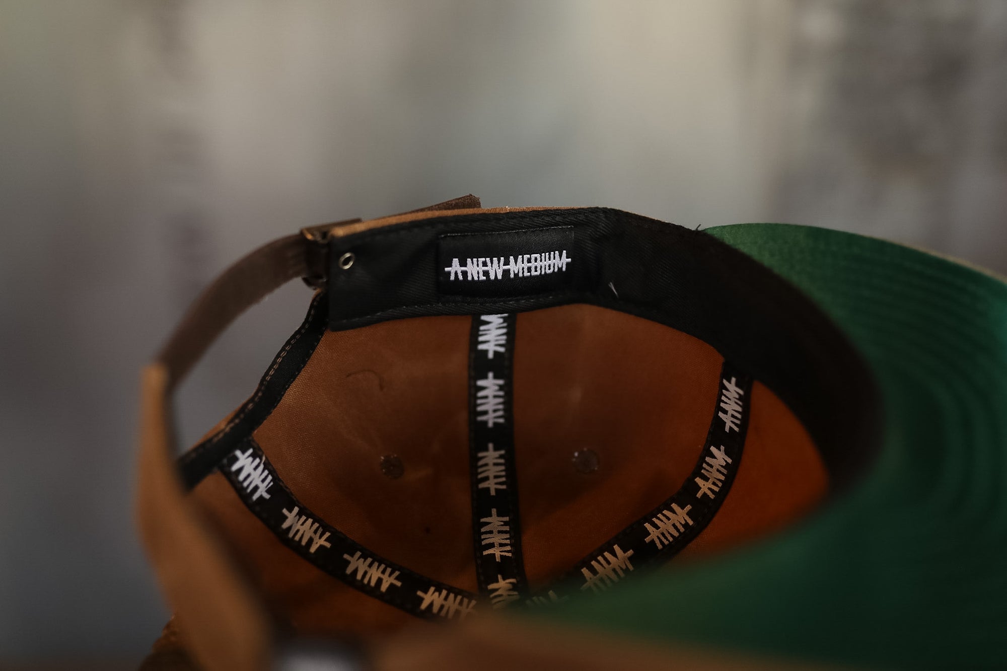 Close-up of a cap with a black adjustable strap featuring white text on a blurred background