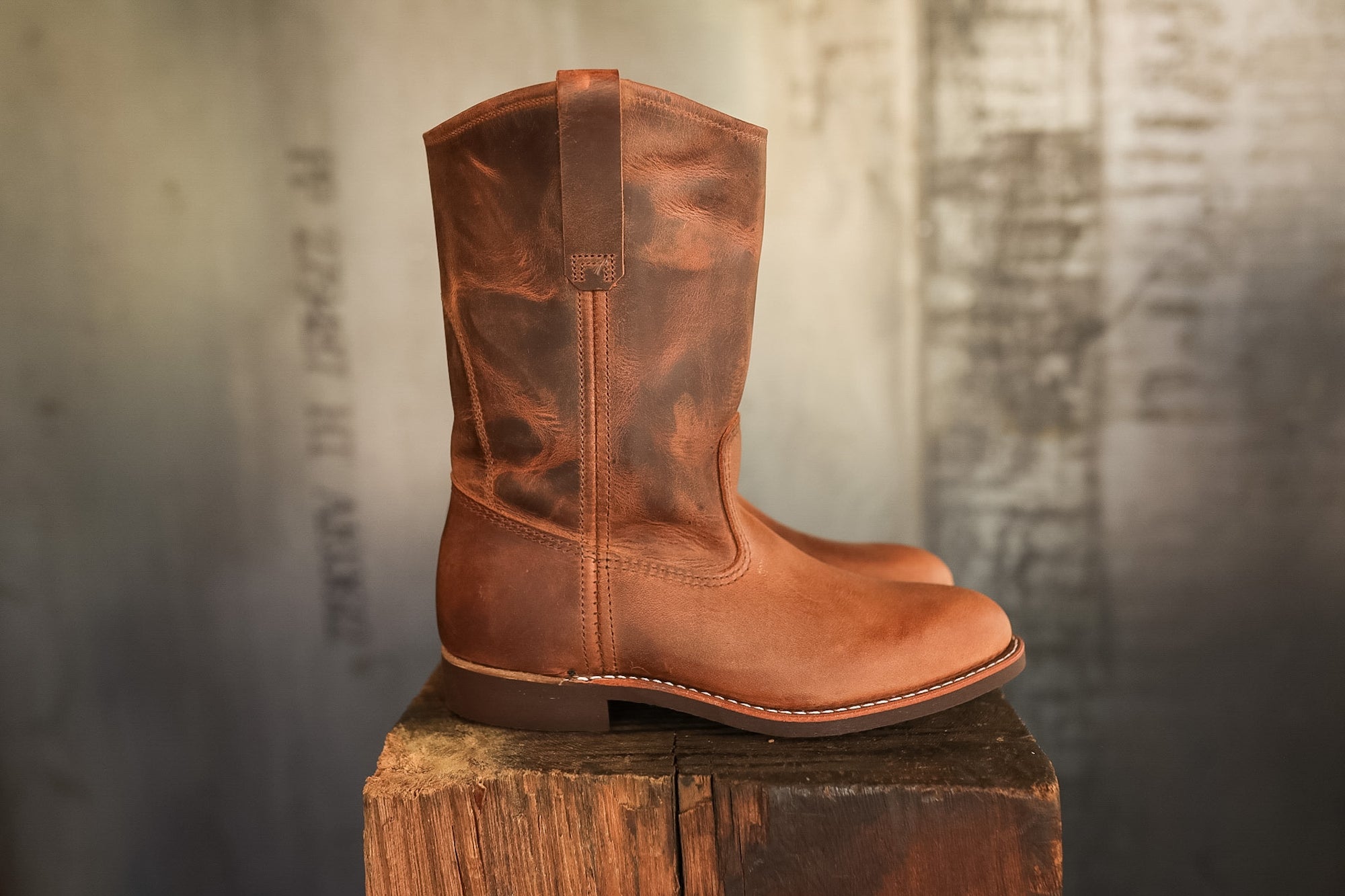Brown leather boot on a wooden block with a textured background