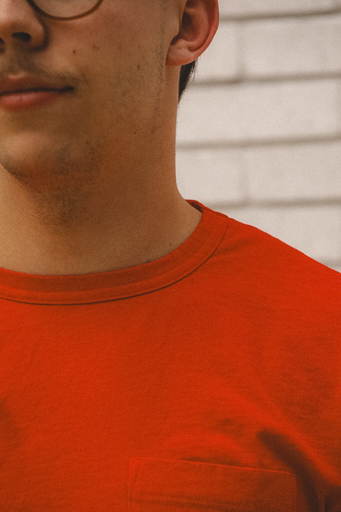 Close-up of a person wearing an orange shirt with a neutral background