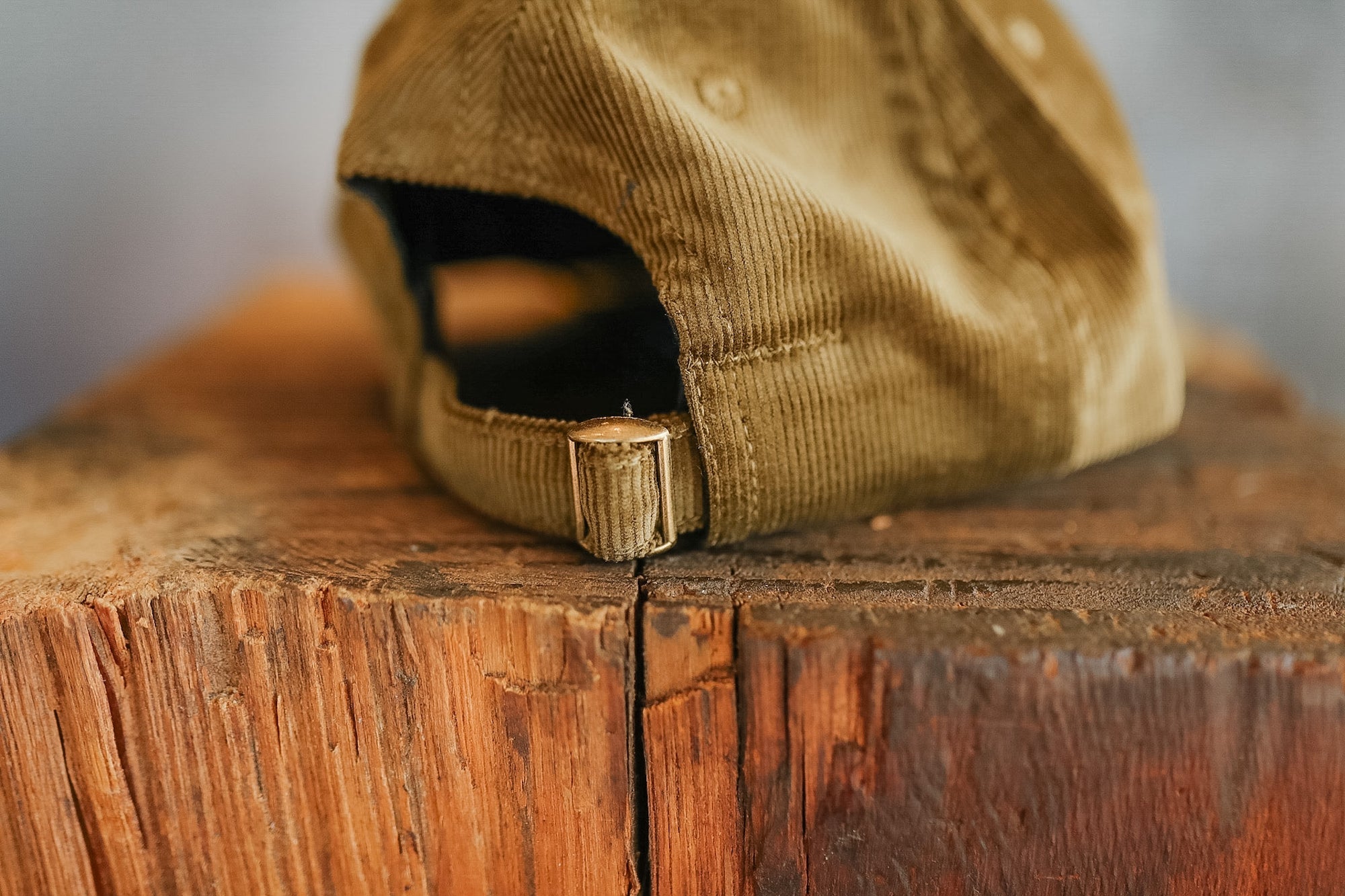 Brown corduroy cap on a wooden surface with a blurred background
