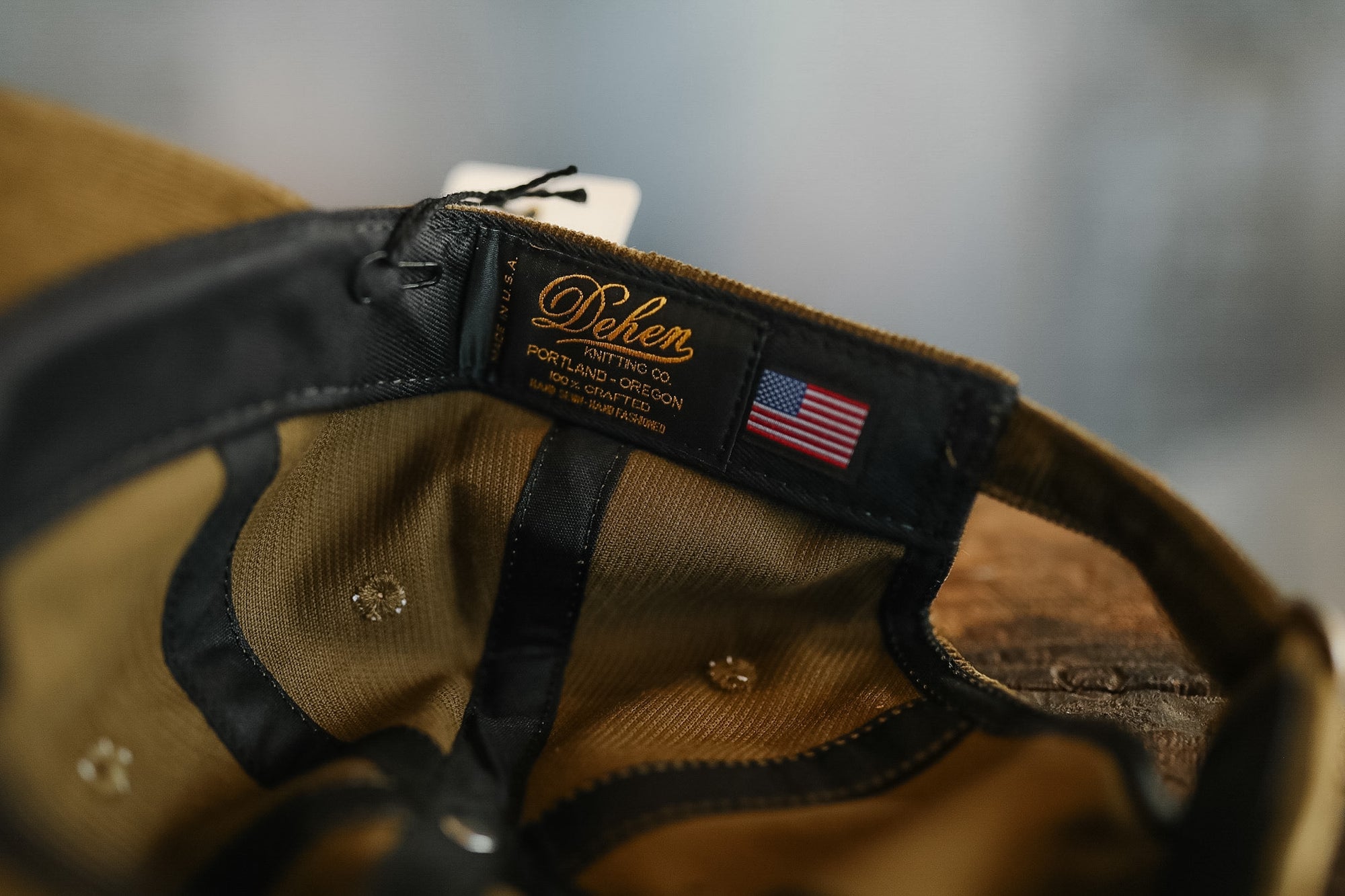 Close-up of a brown cap with a brand label and American flag patch on a blurred background