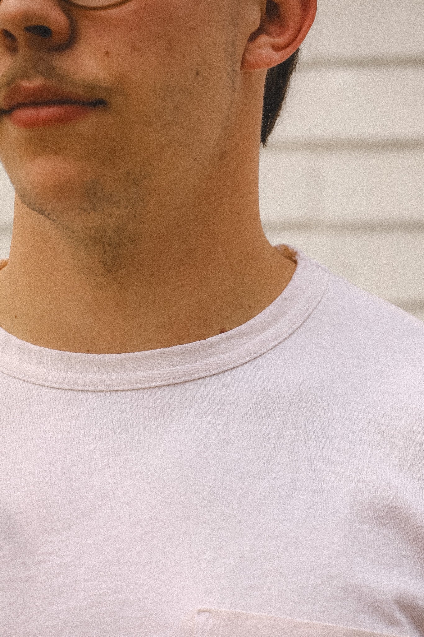 Close-up of a person wearing a white t-shirt with a neutral background