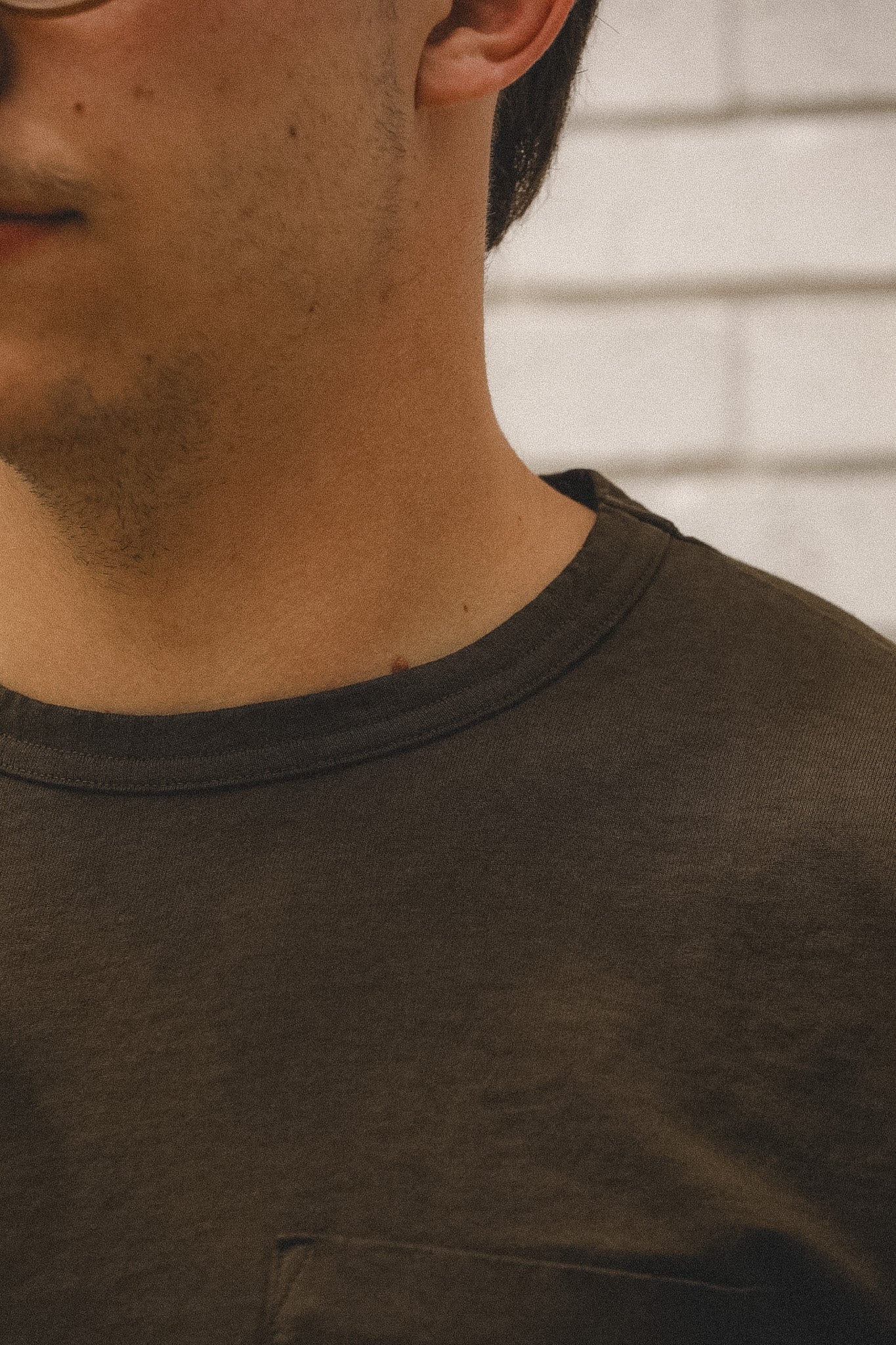 Close-up of a person wearing a dark brown t-shirt with a neutral background