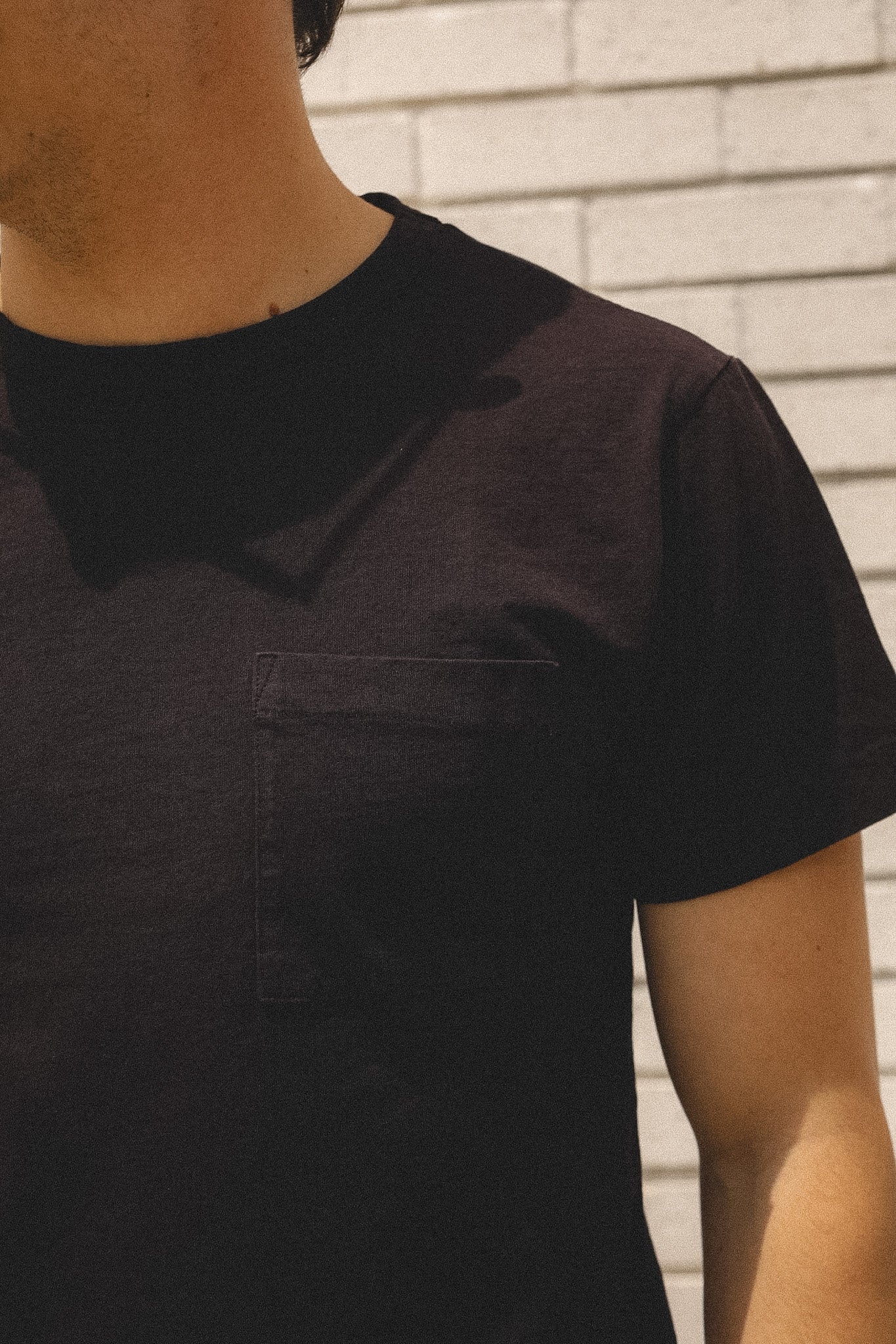 Person wearing a black t-shirt with a collar against a neutral background