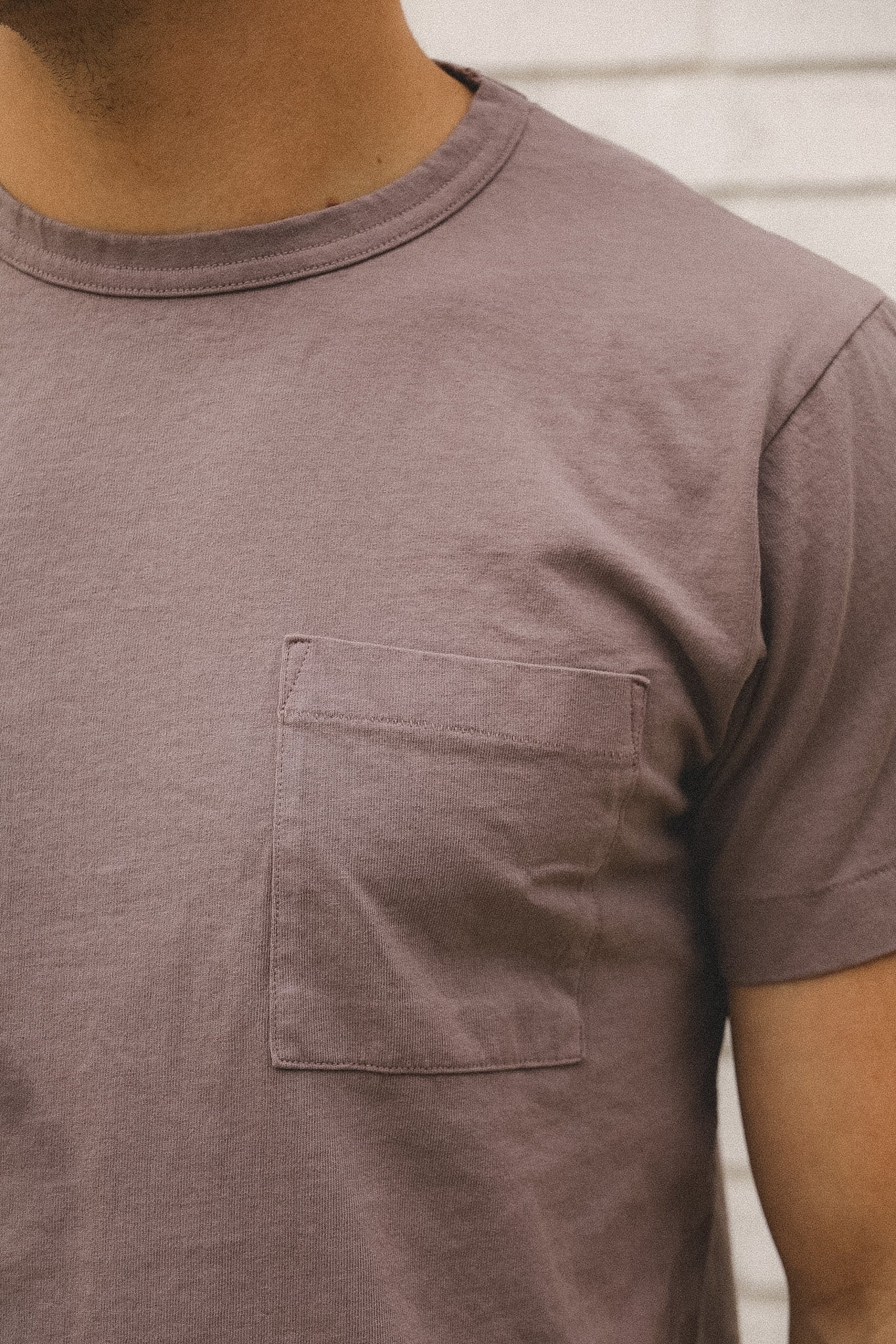 Close-up of a person wearing a brown t-shirt with a pocket.