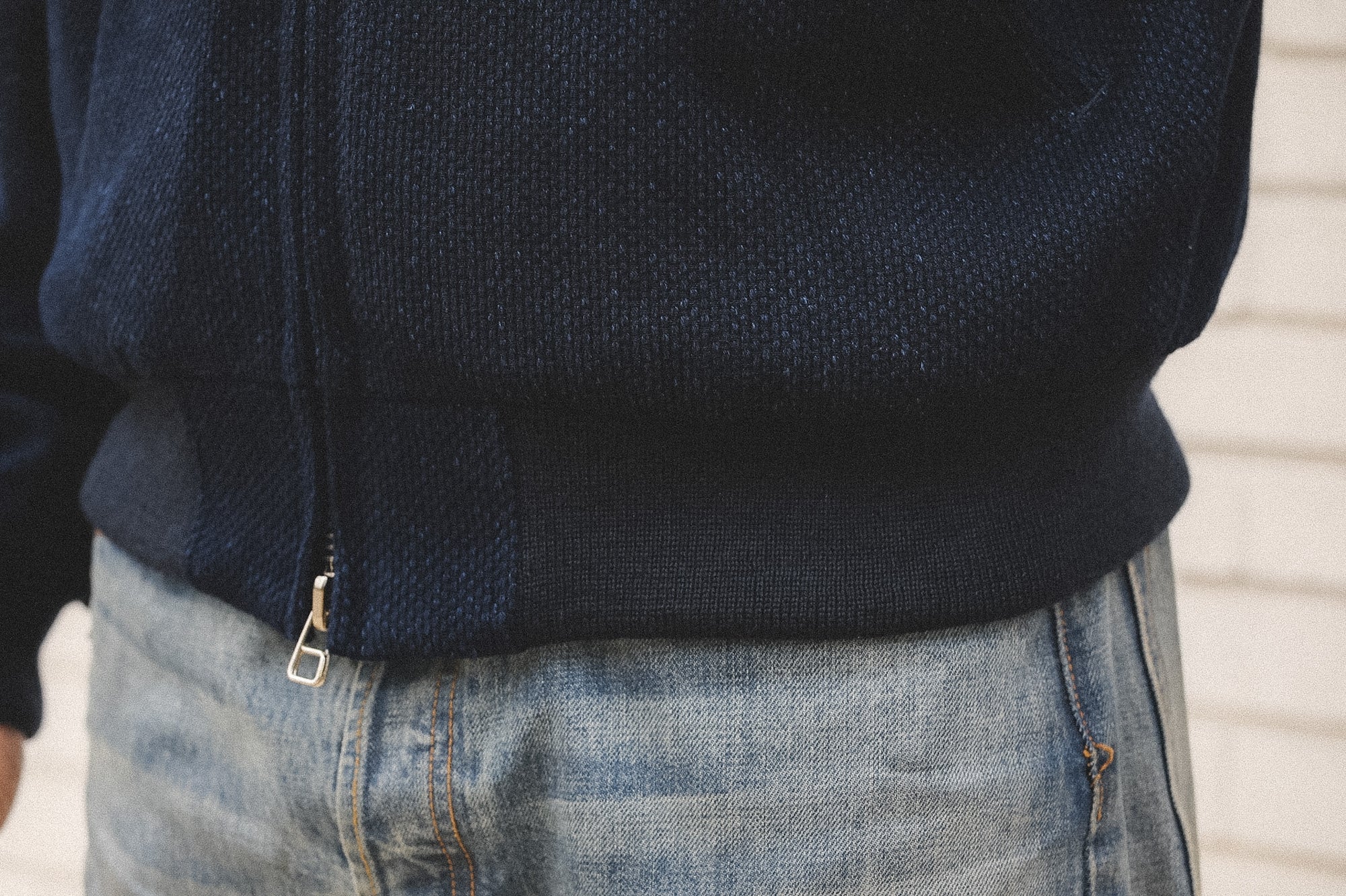 Navy jacket and blue jeans worn by a person against a neutral background