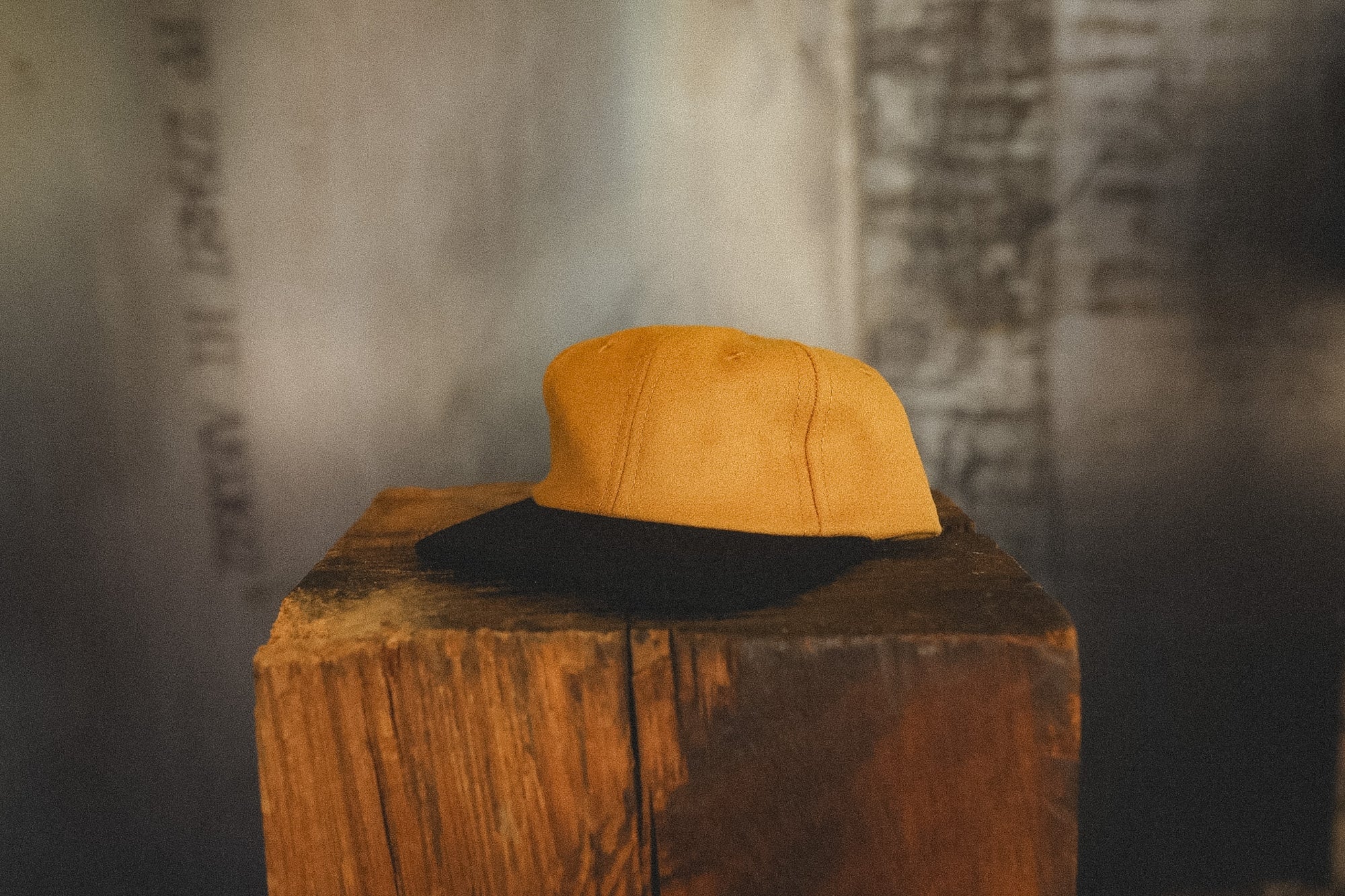 Yellow and black cap on a wooden block with a textured wall background
