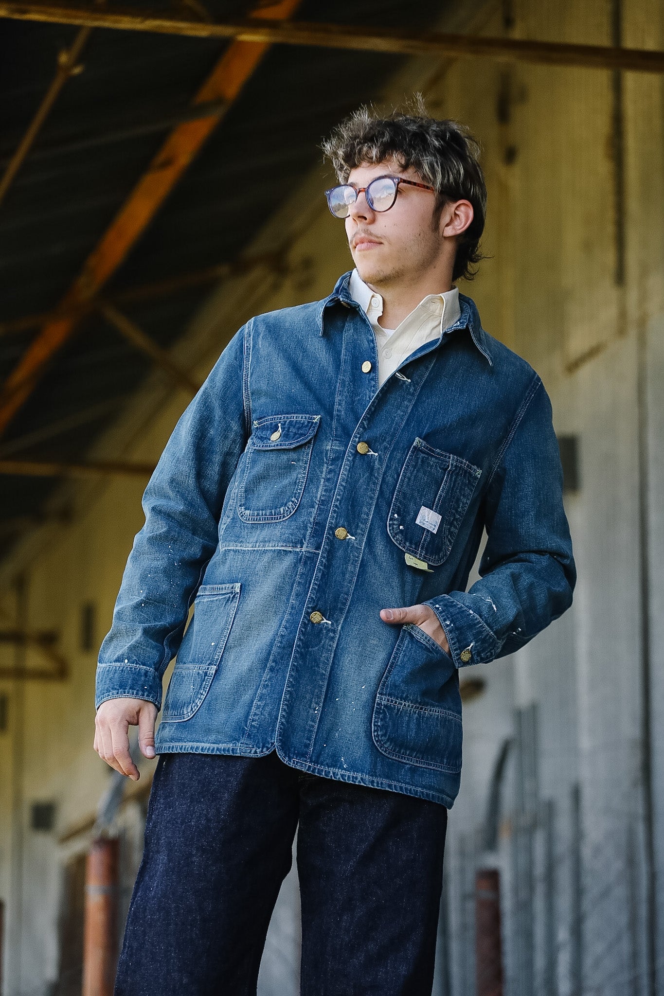 Man wearing a blue denim jacket in an industrial setting