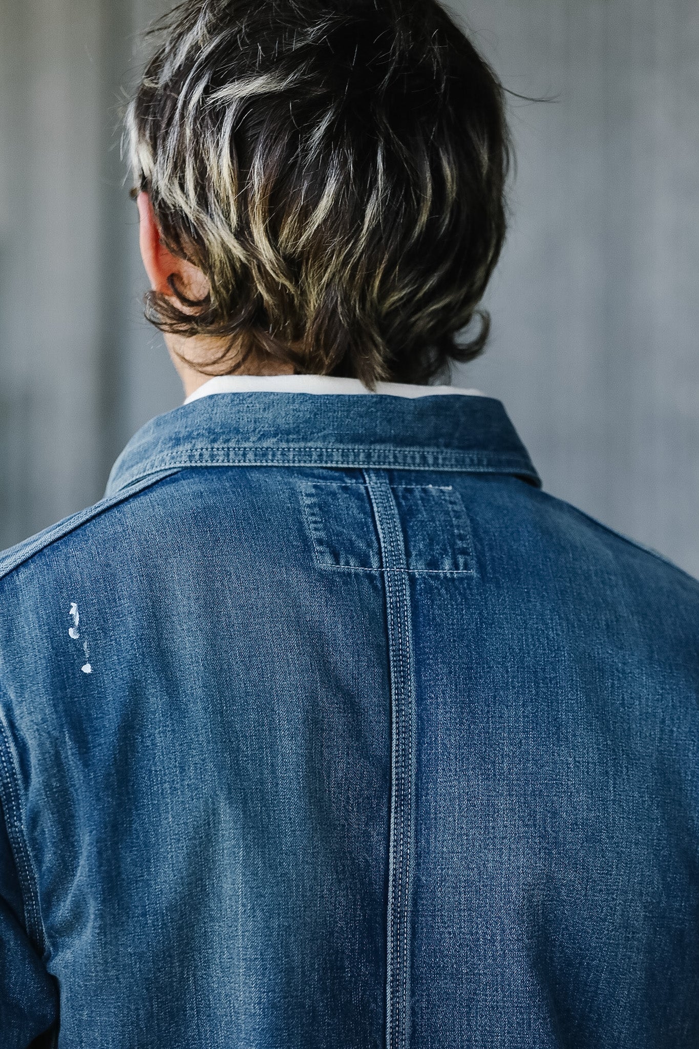 Person wearing a blue denim jacket with a neutral background