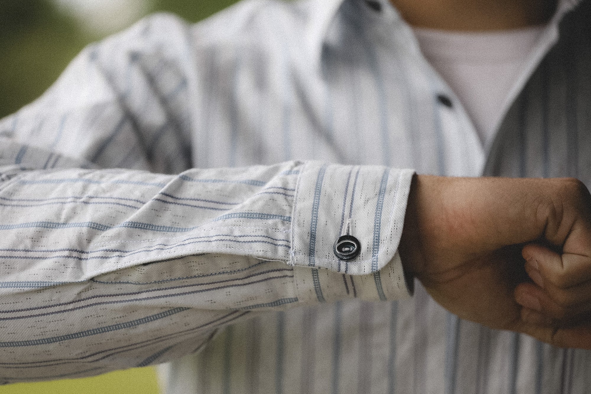 Close-up of a person wearing a striped shirt with rolled-up sleeve.