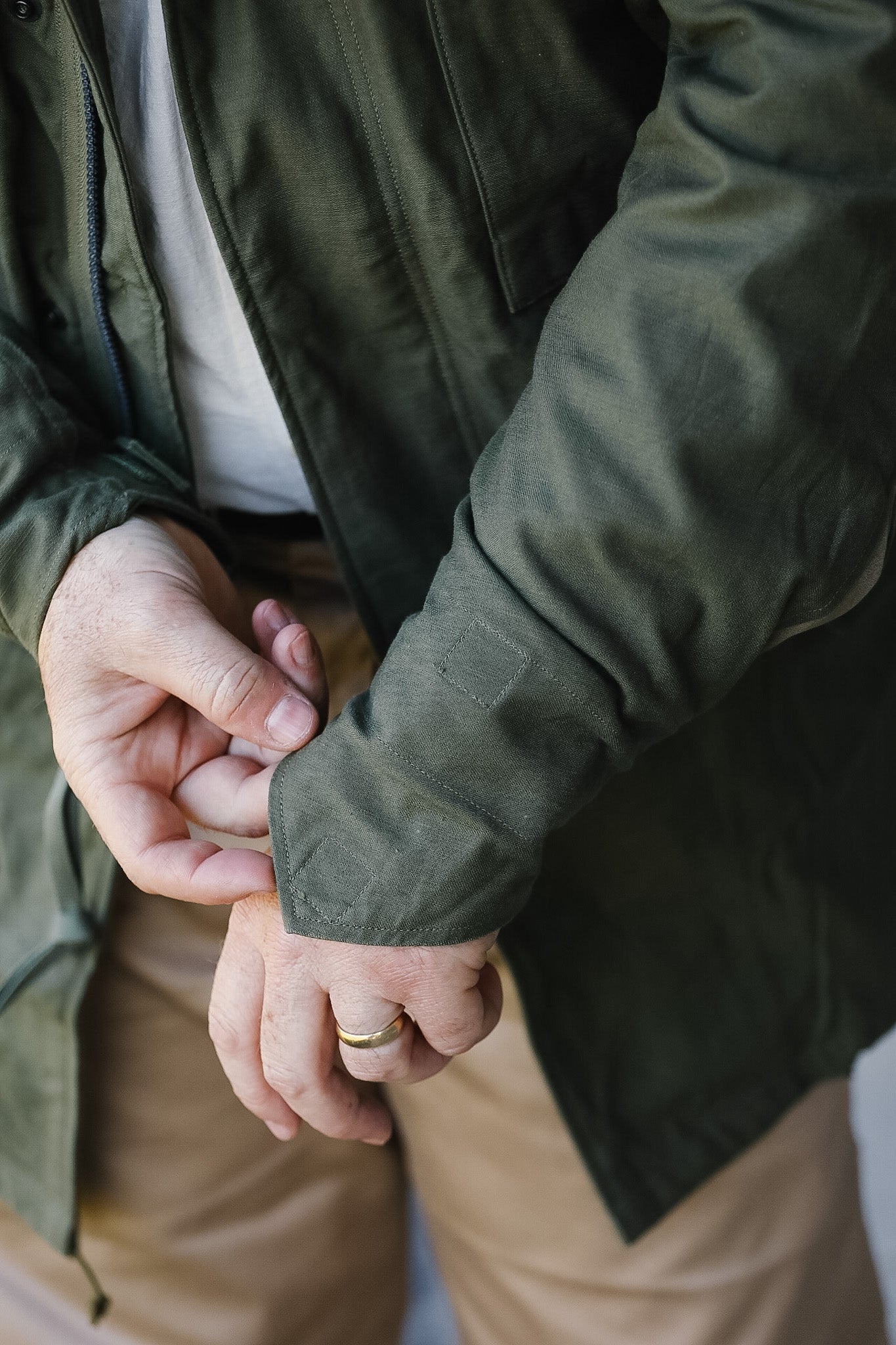 Two people holding hands, one wearing a green jacket and beige pants, the other in a dark jacket.