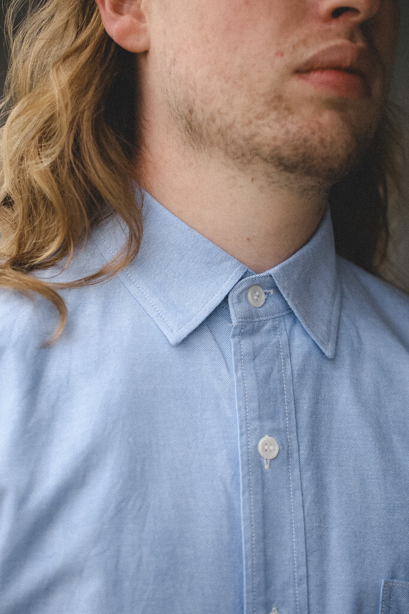 Close-up of a person wearing a light blue shirt with a neutral background