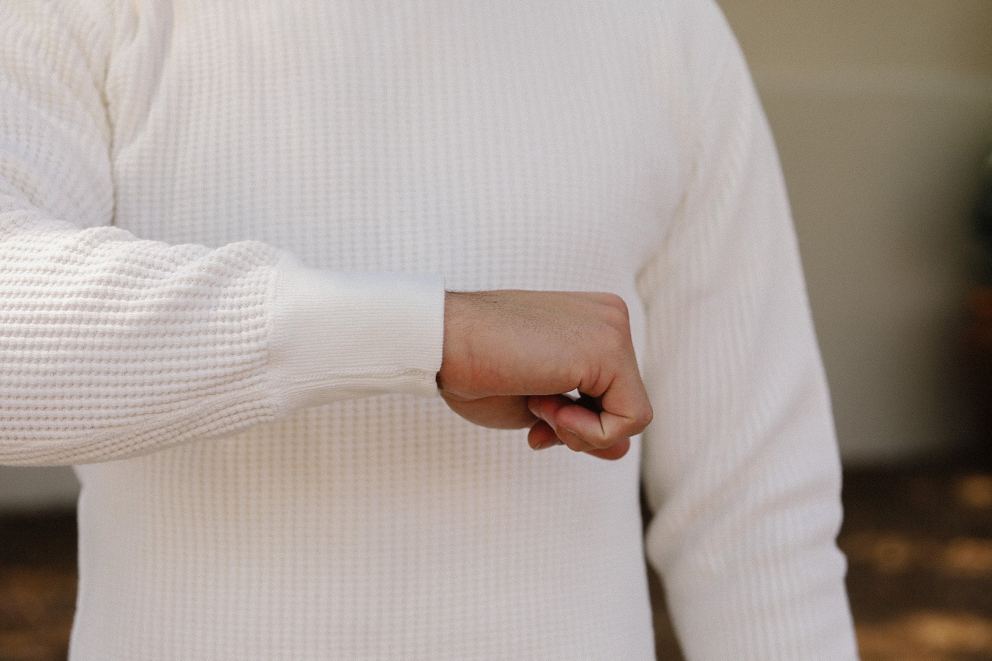 Person wearing a white sweater with a blurred background