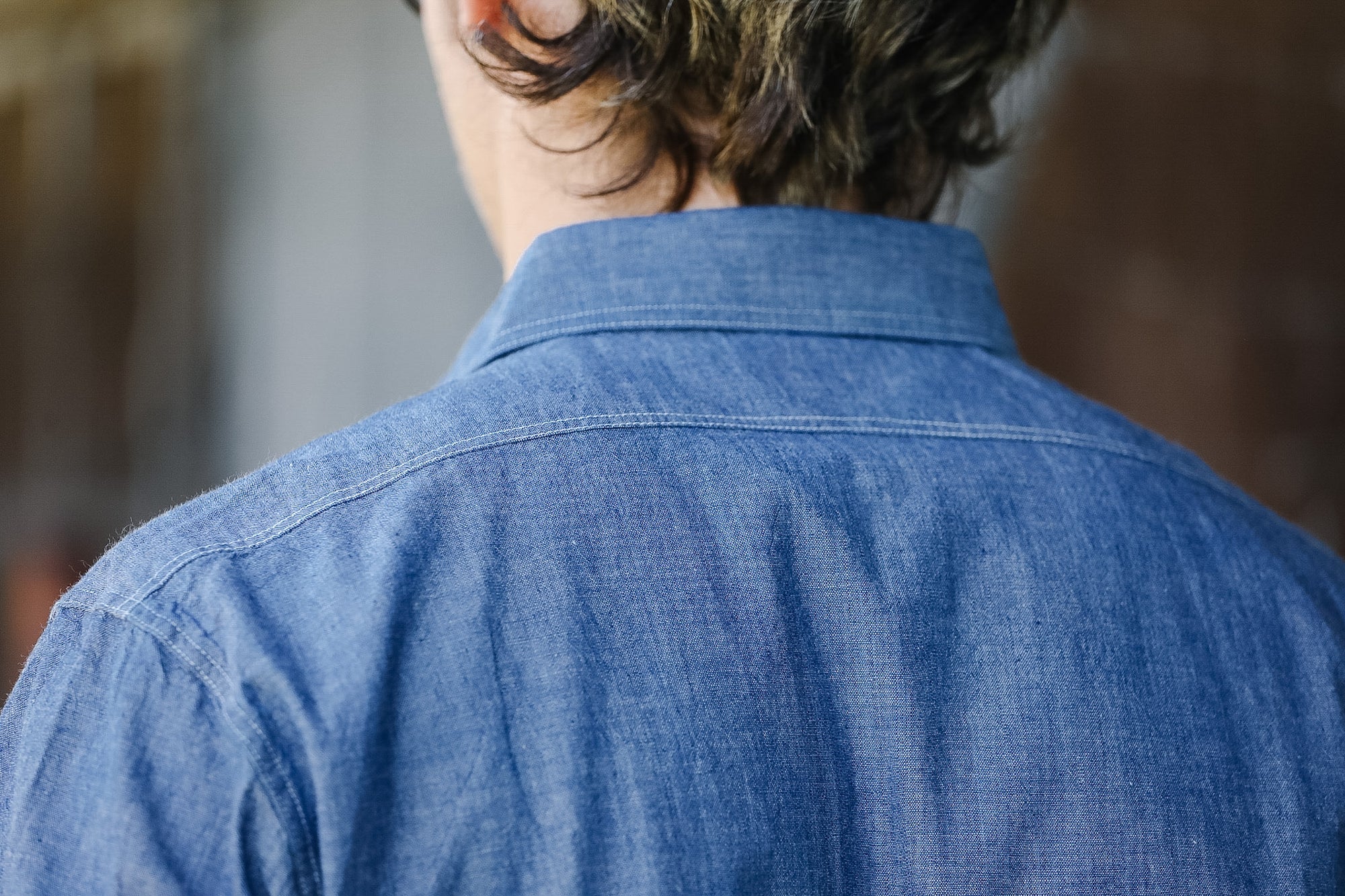 Person wearing a blue denim shirt with a blurred background