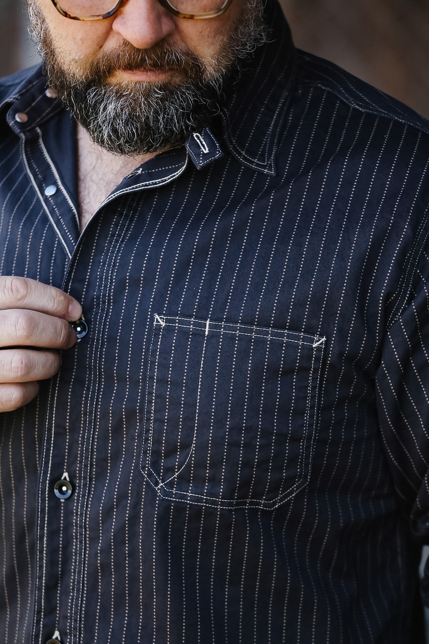 Man wearing a dark pinstripe shirt with a blurred background