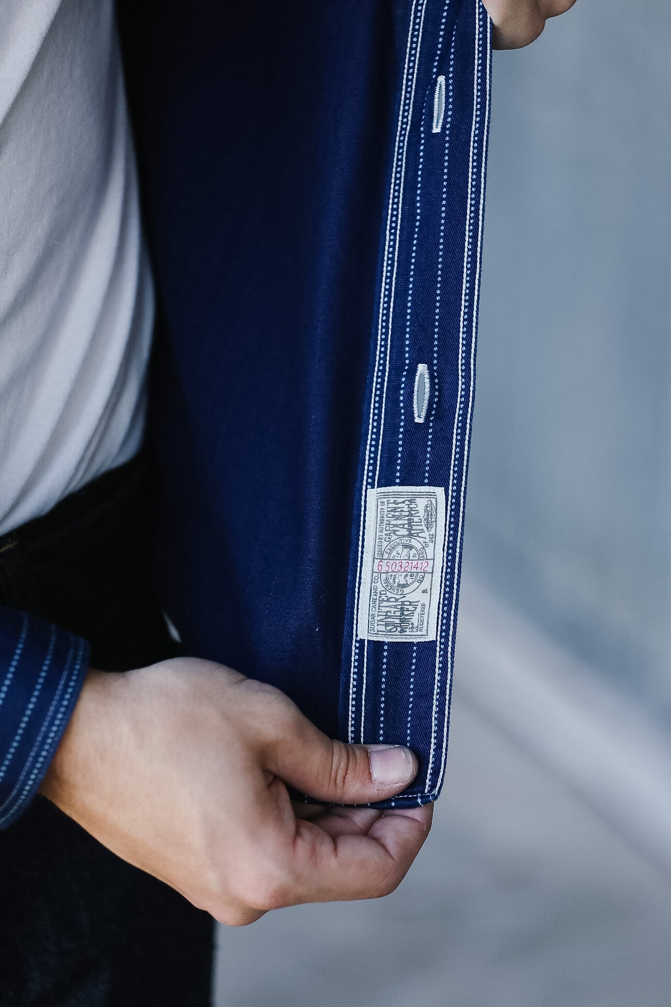 Close-up of a person holding a navy blue denim jacket with a brand label.