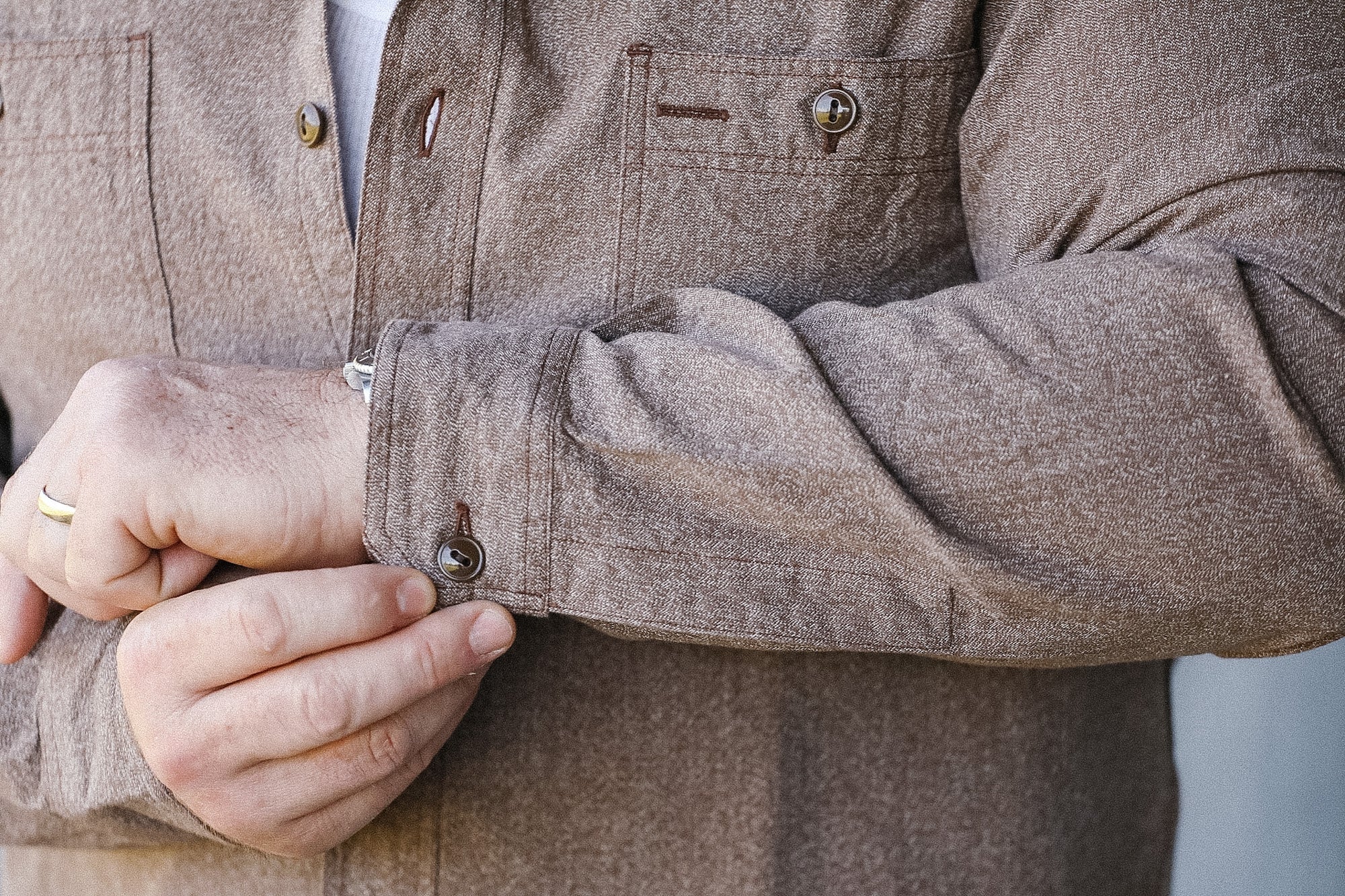 Close-up of a person wearing a brown jacket with a blurred background