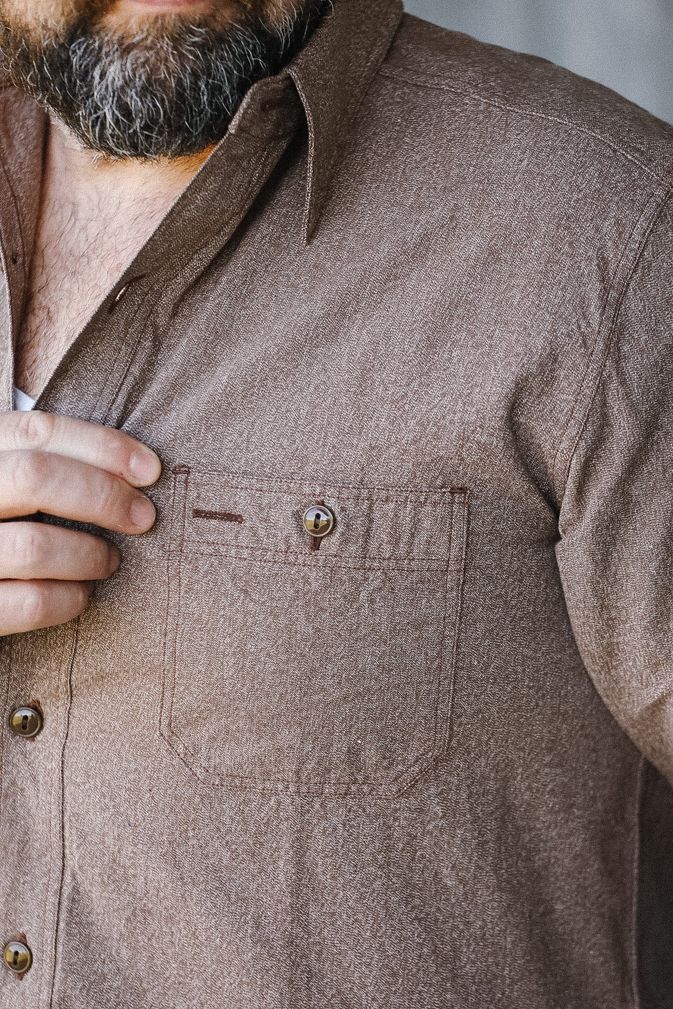 Close-up of a brown button-up shirt with a pocket and buttons.