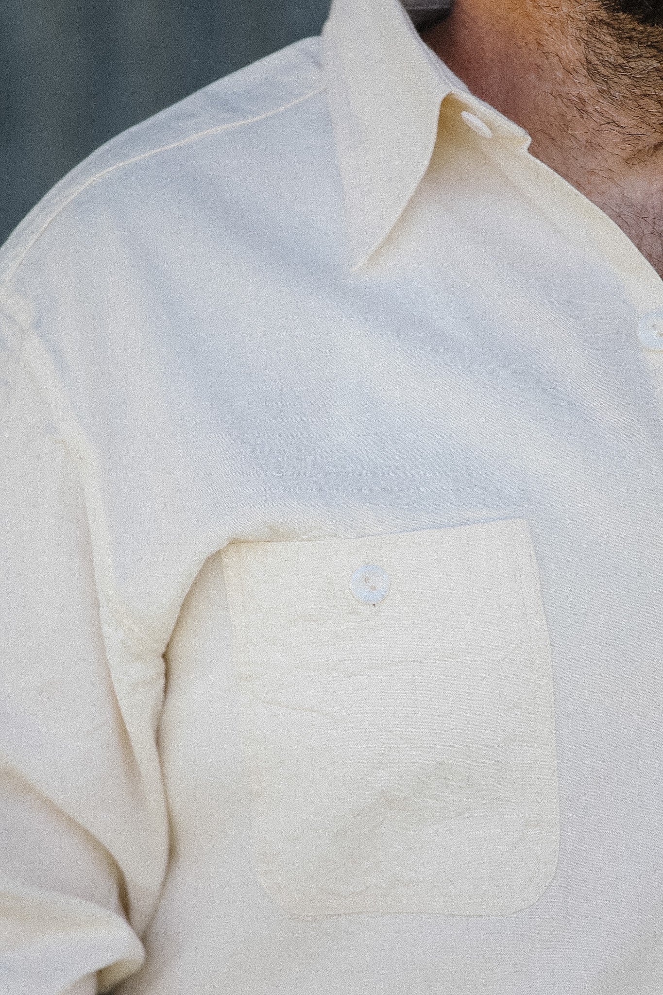 Close-up of a light-colored shirt with a pocket and collar.